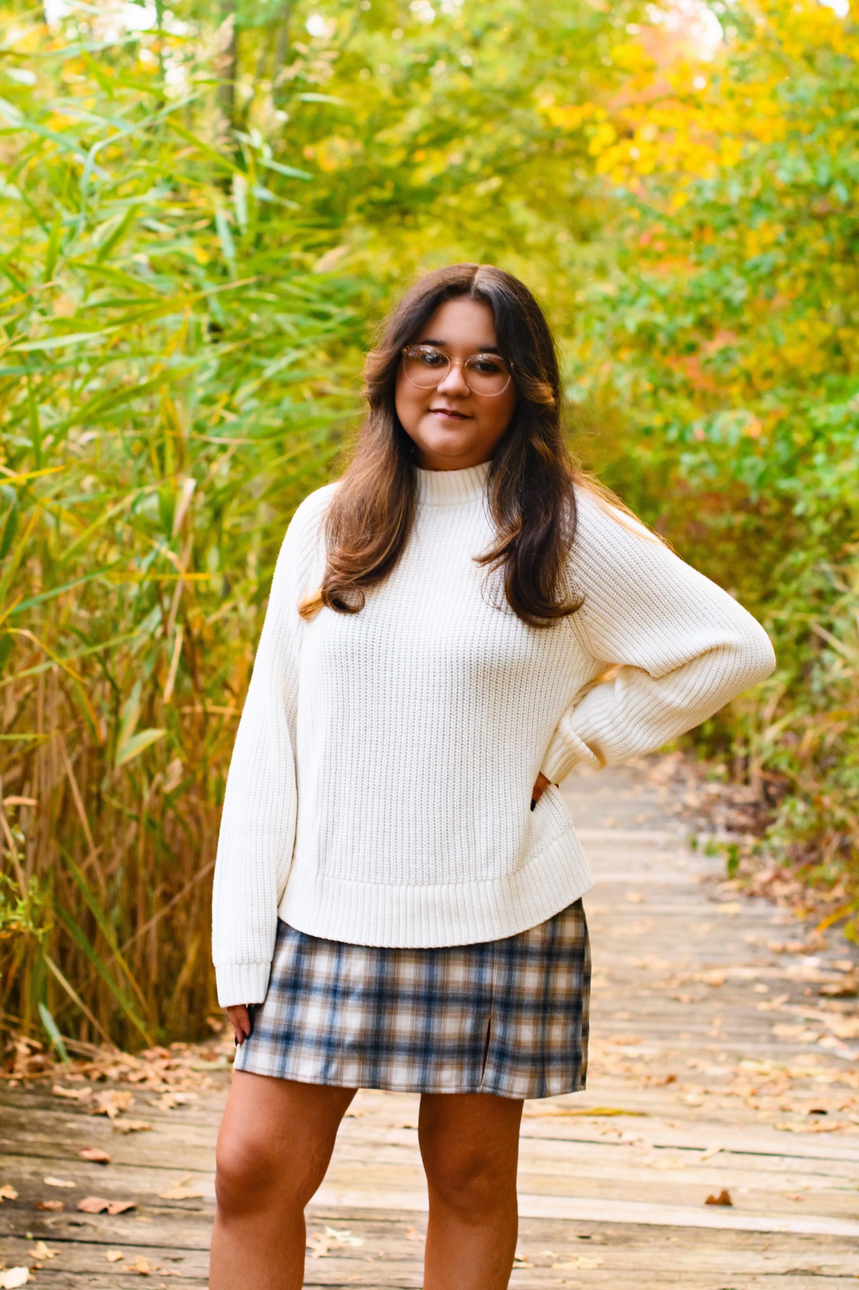 Allen Park senior portrait of Carmen standing outdoors in a white sweater and plaid skirt