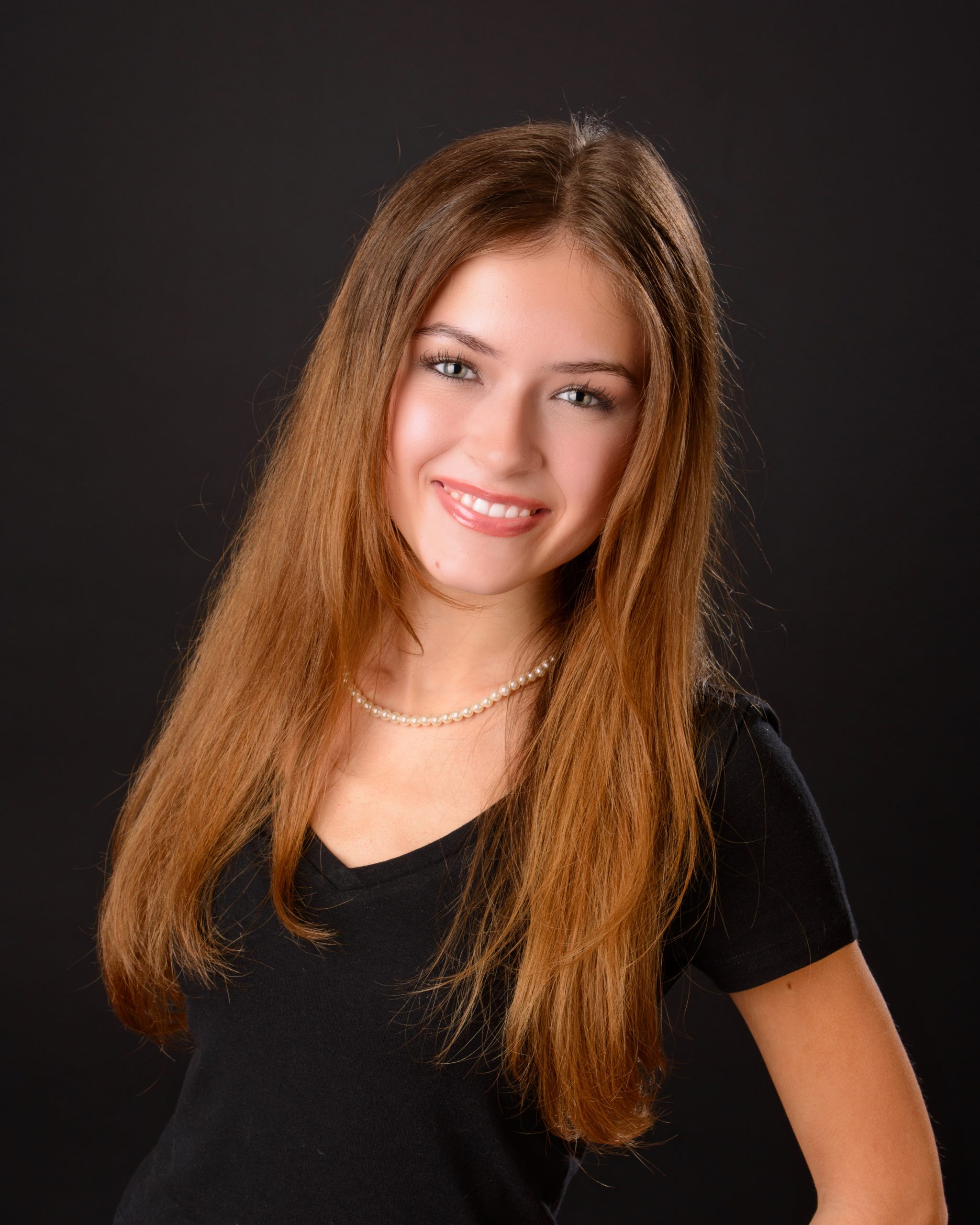 Senior photo session featuring green graduation cap and gown, holding cap in mansion studio setting