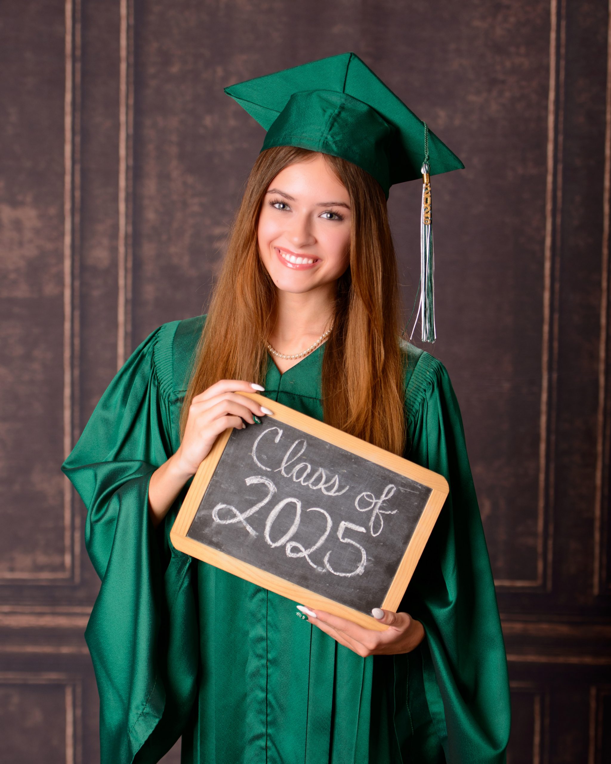 Senior photo session featuring green graduation cap and gown, holding cap in mansion studio setting