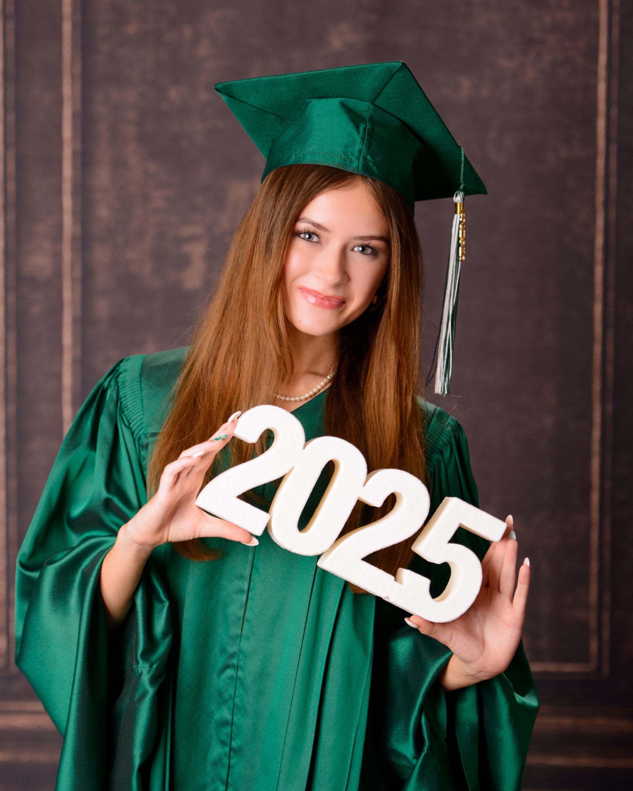 Senior photo session featuring green graduation cap and gown, holding cap in mansion studio setting