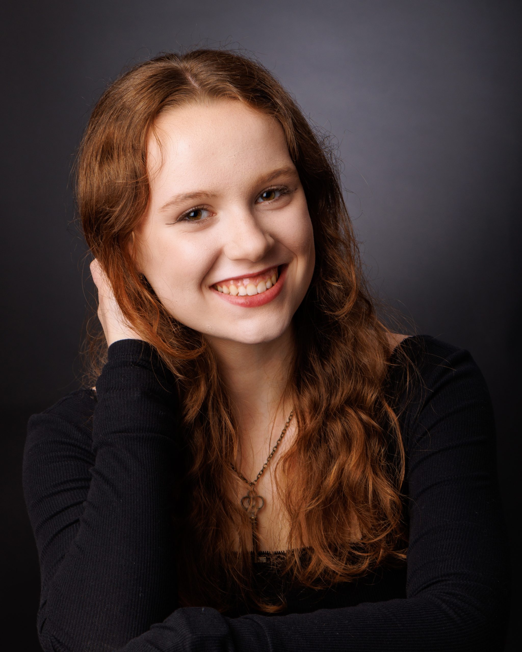 Female student holding Allen Park Varsity jacket with equestrian design in studio session