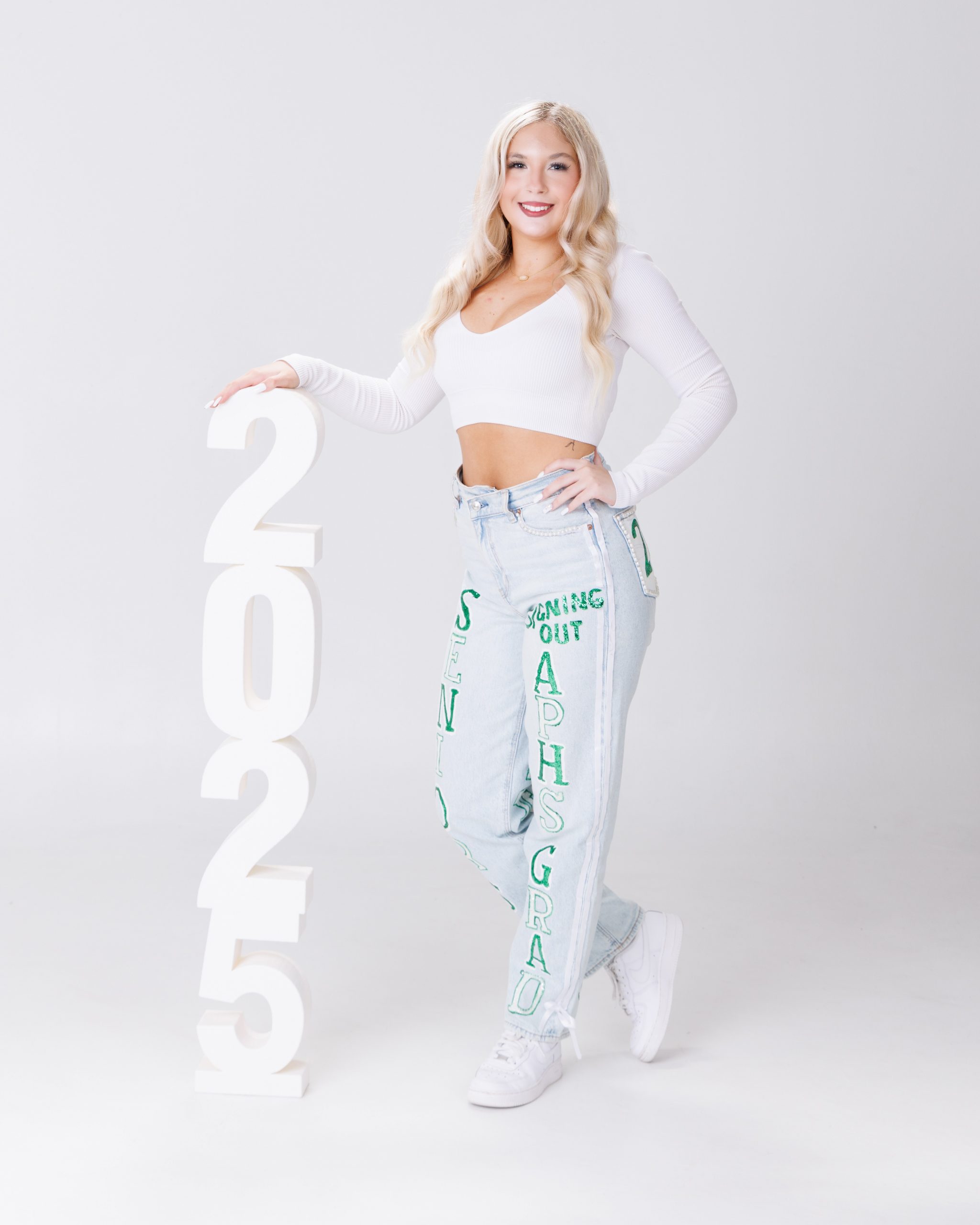 Two young women posing together with large '2023' letters in a white studio setting