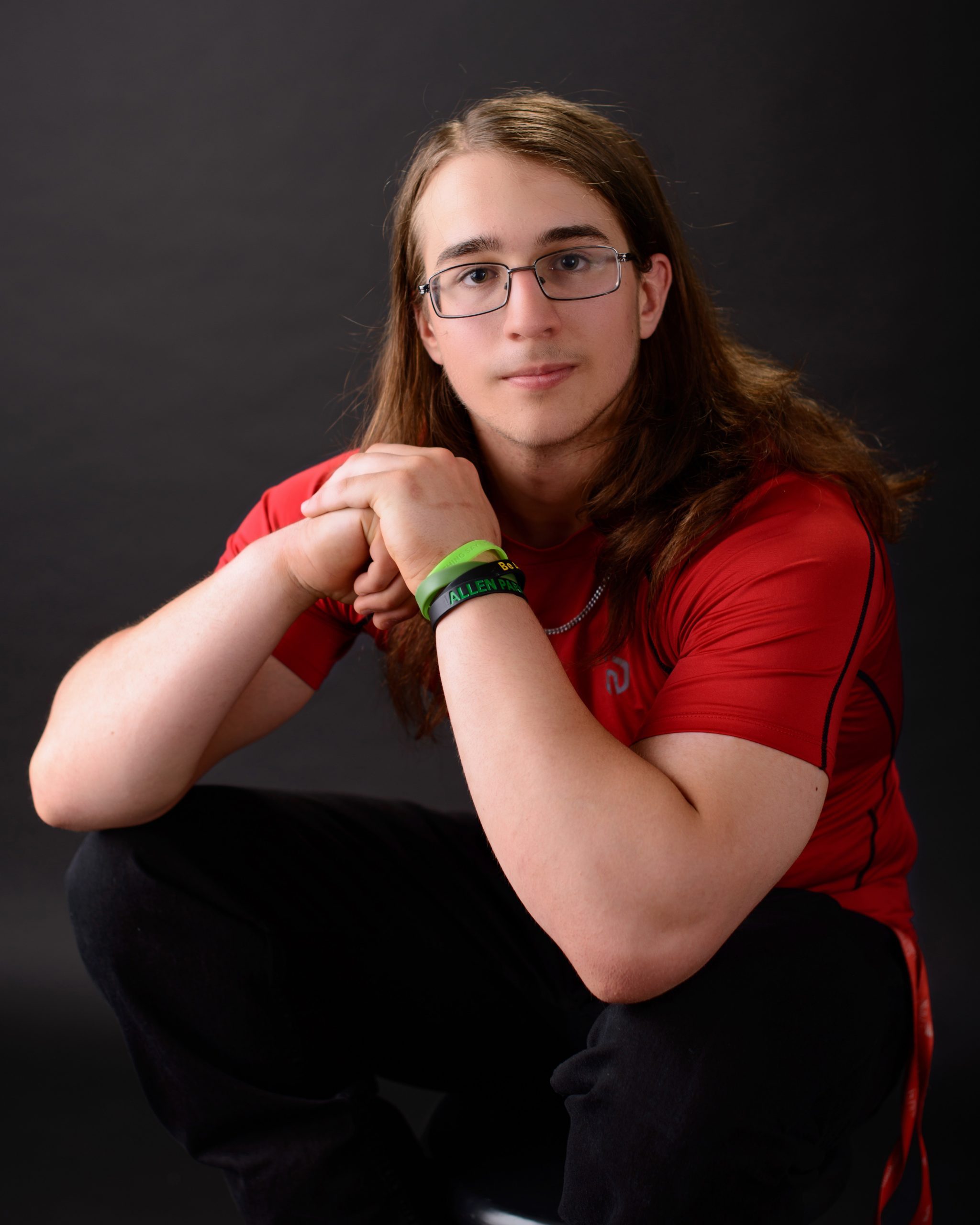high school senior athlete sitting on floor in athletic wear, arms crossed, wearing brown boots