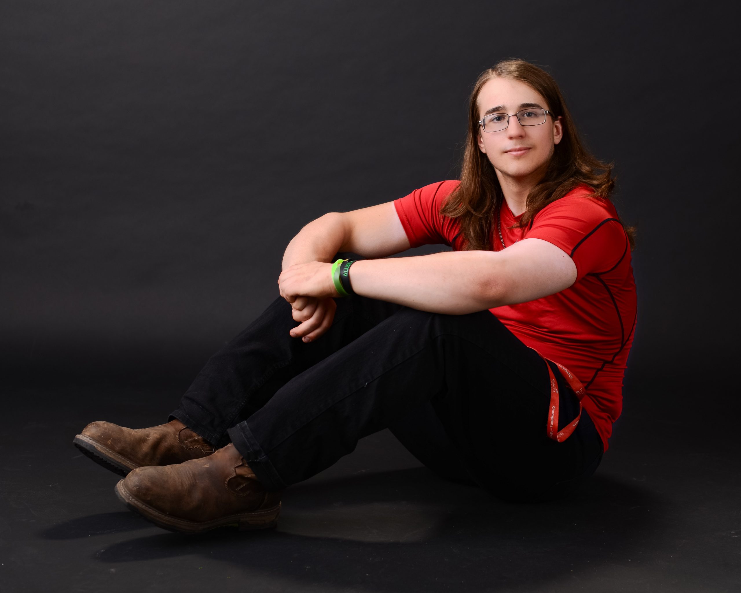 high school senior athlete sitting on floor in athletic wear, arms crossed, wearing brown boots