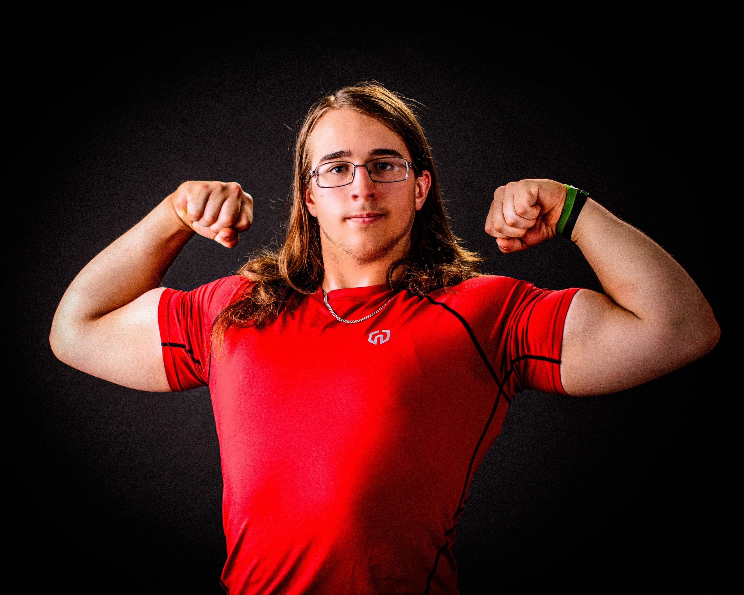 high school senior athlete sitting on floor in athletic wear, arms crossed, wearing brown boots
