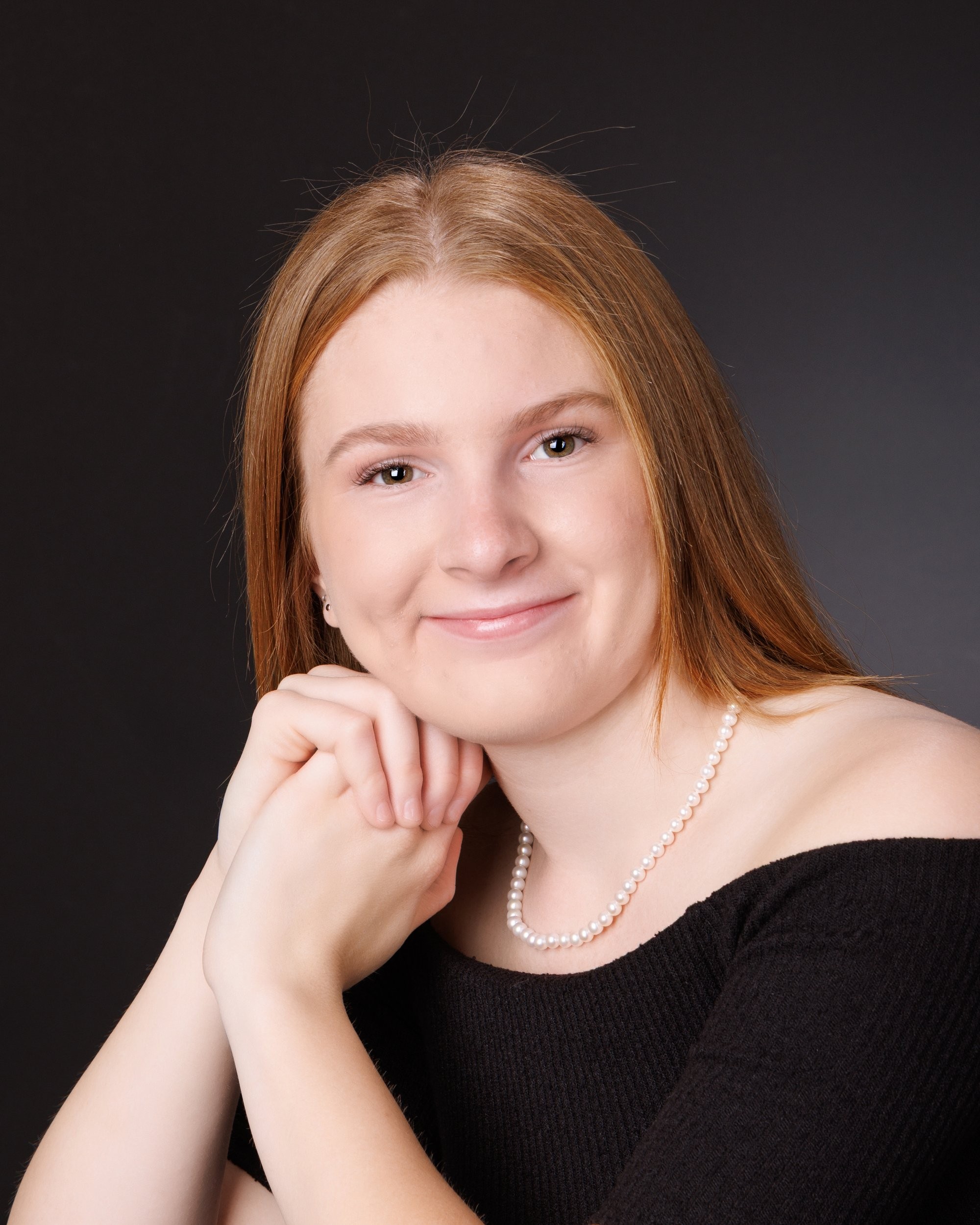 Bailey holds large '2026' numbers while standing in a white studio setting for her senior photography shoot