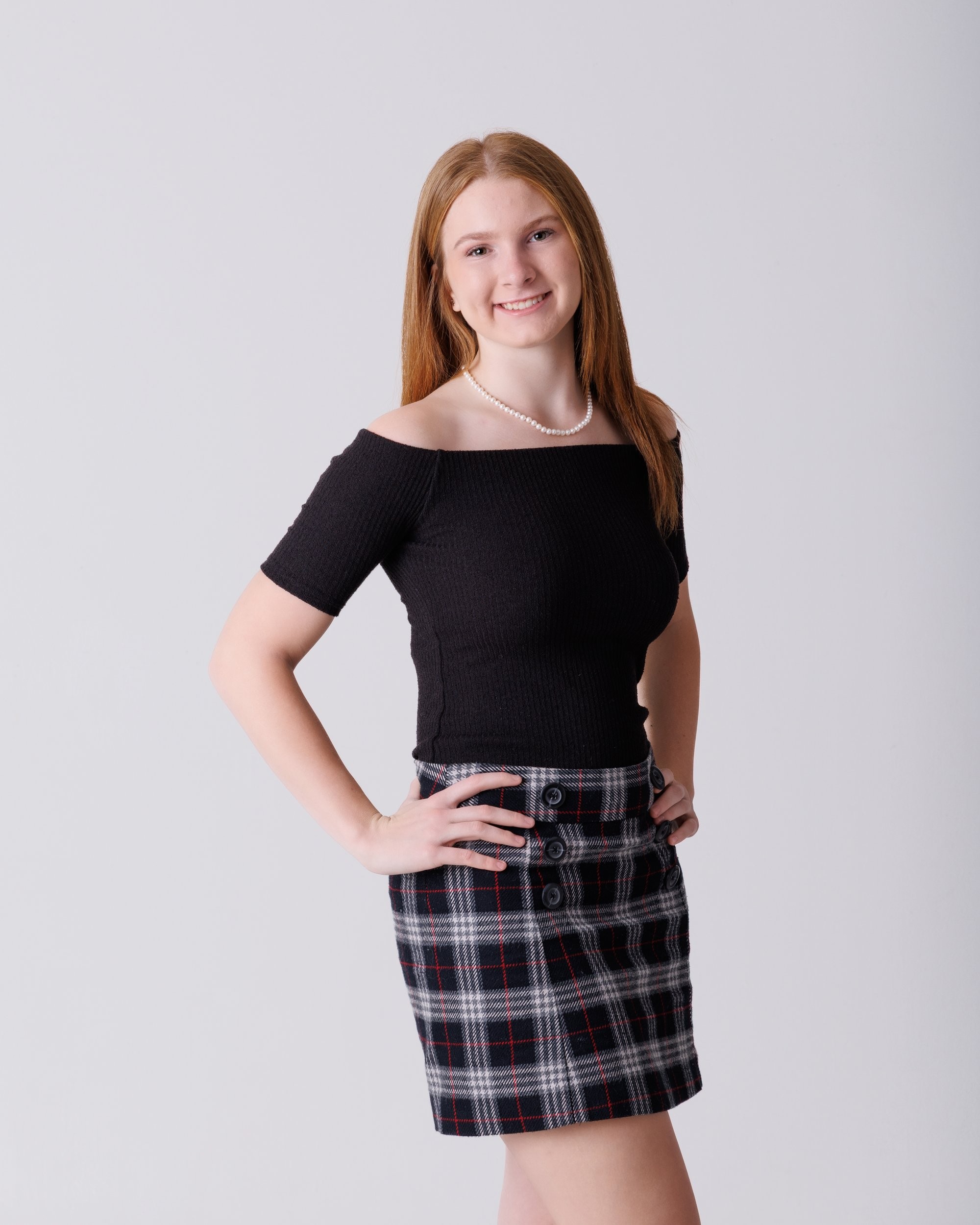 Bailey holds large '2026' numbers while standing in a white studio setting for her senior photography shoot