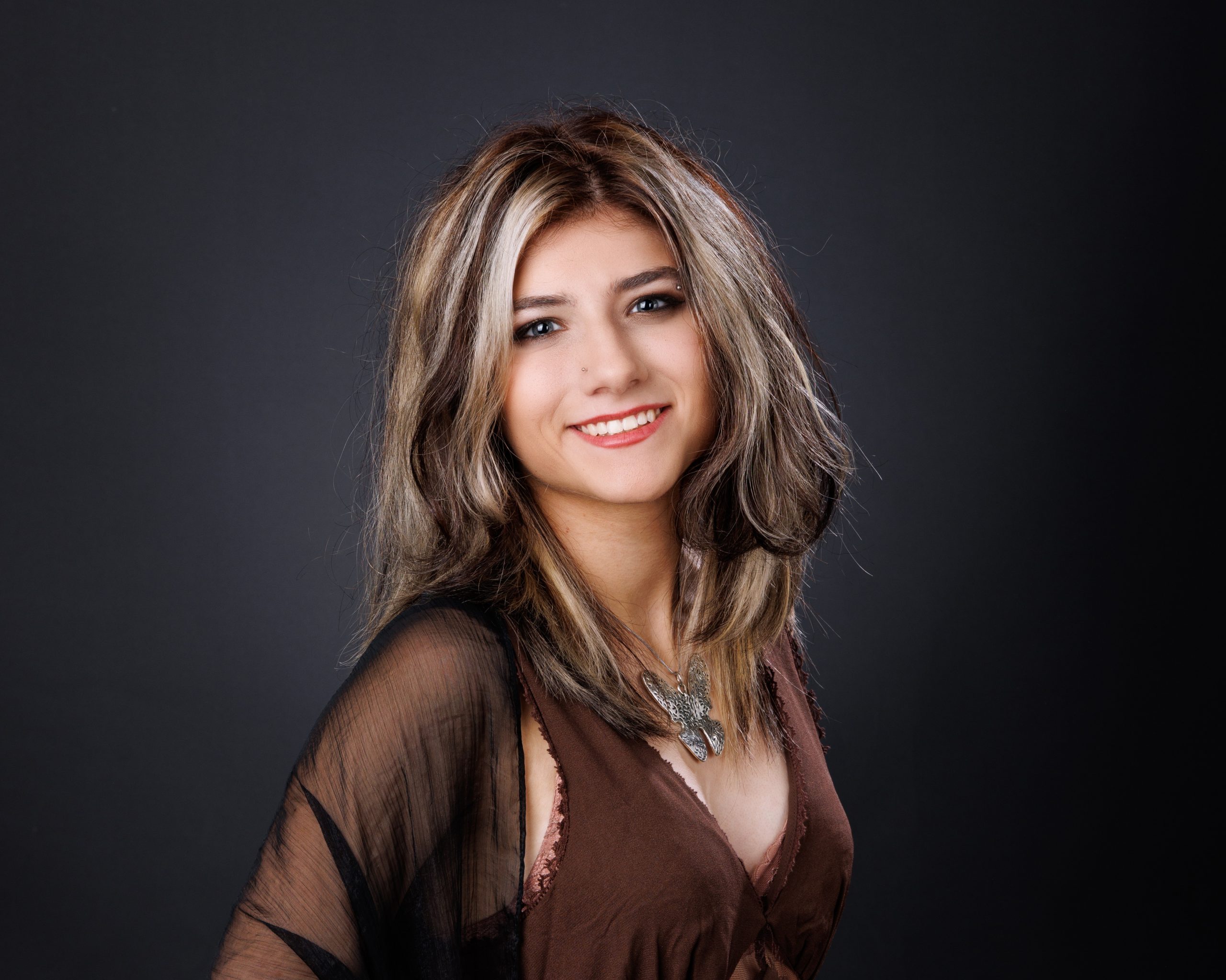 Brooke's senior portrait featuring a brown dress, sheer overlay, and dark backdrop during an Allen Park photo session
