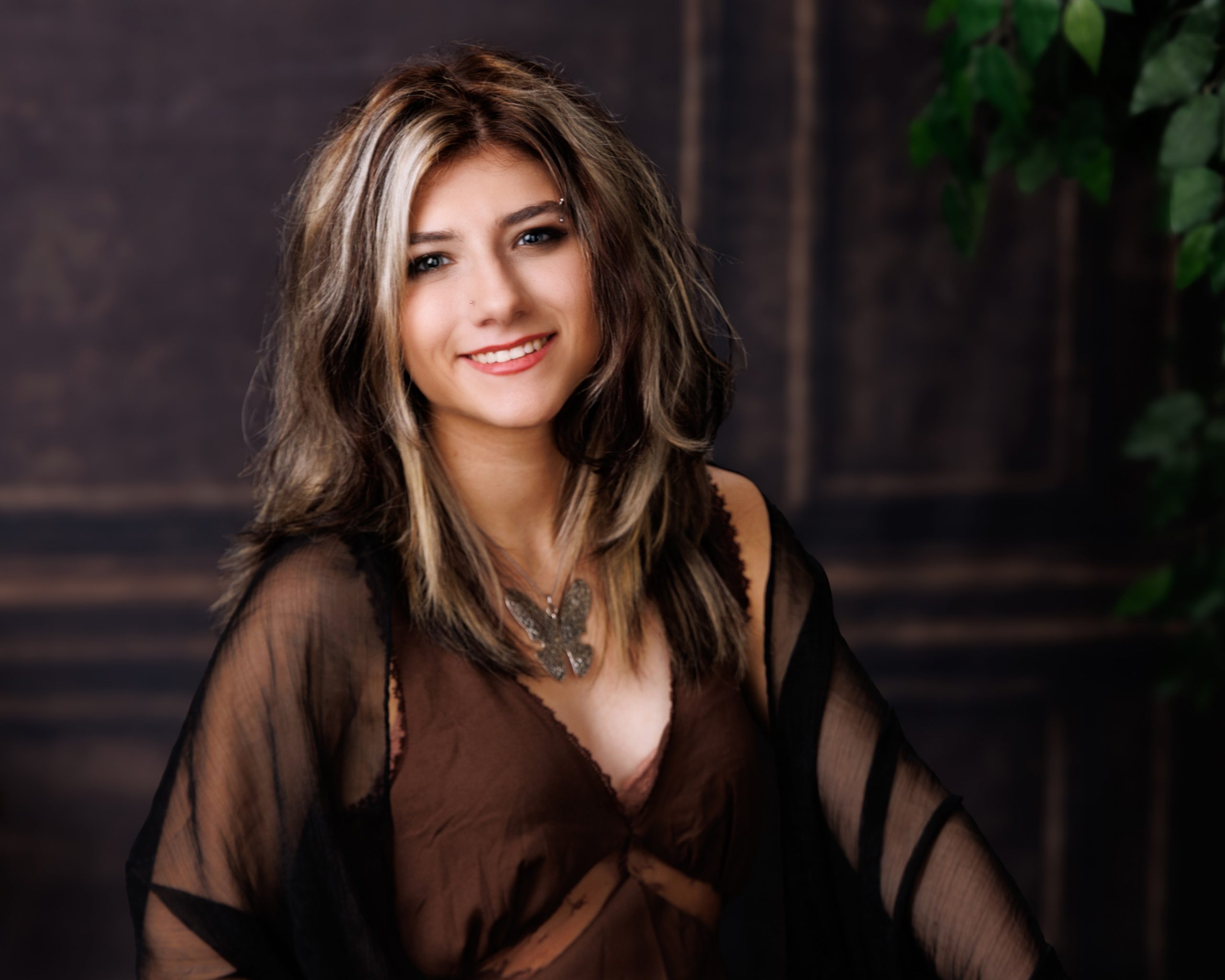 Brooke seated with stacked books in green chair for a Downriver senior photography shoot at Studio ONE