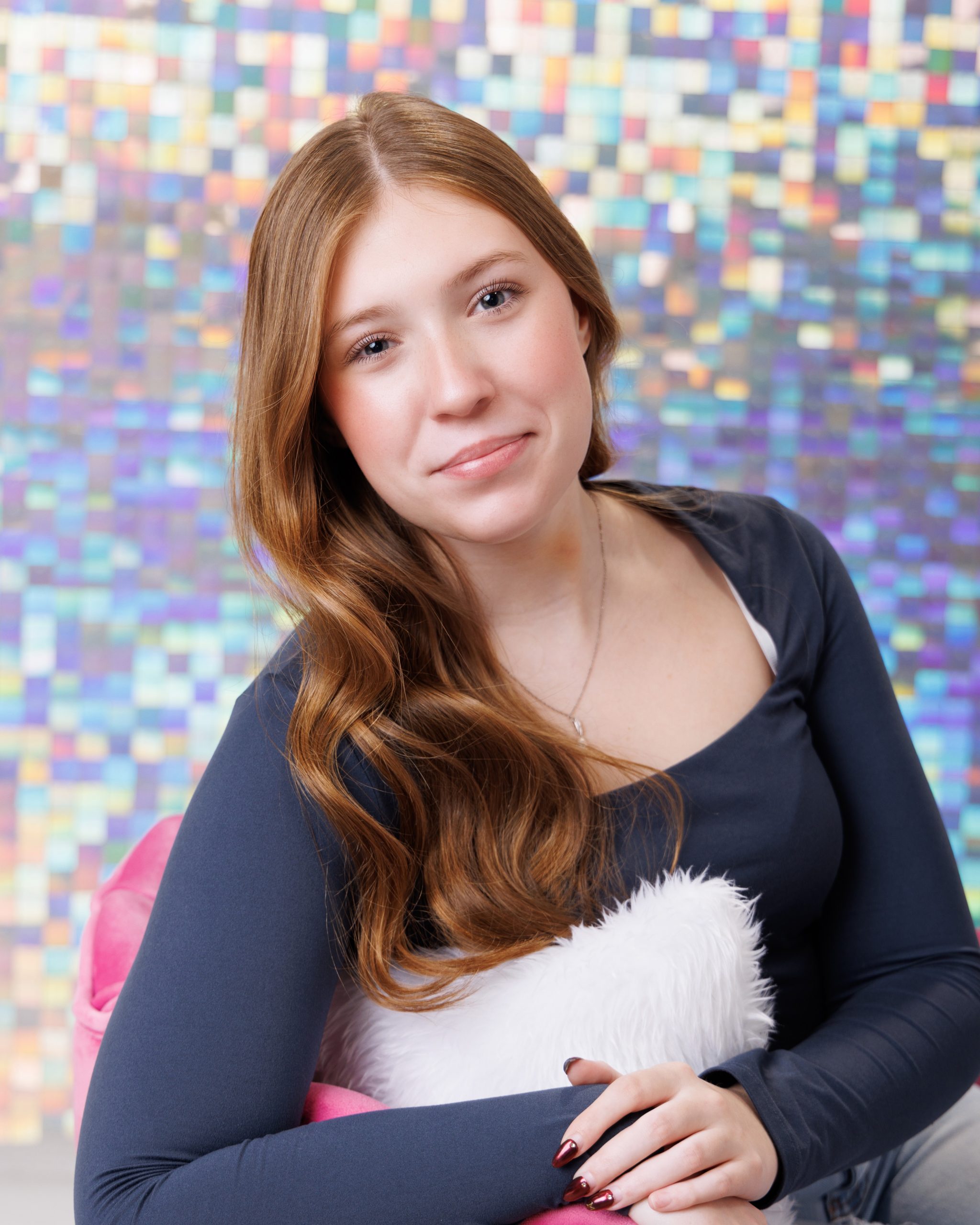 Senior portrait of student holding 'Class of 2025' sign against glitter wall backdrop