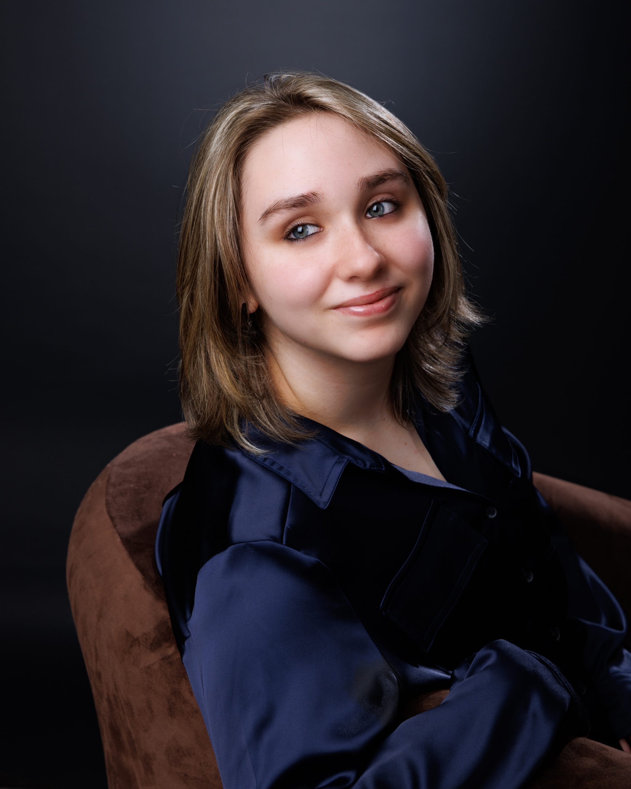 Emma posing with a stack of vintage books during her Allen Park senior photo session