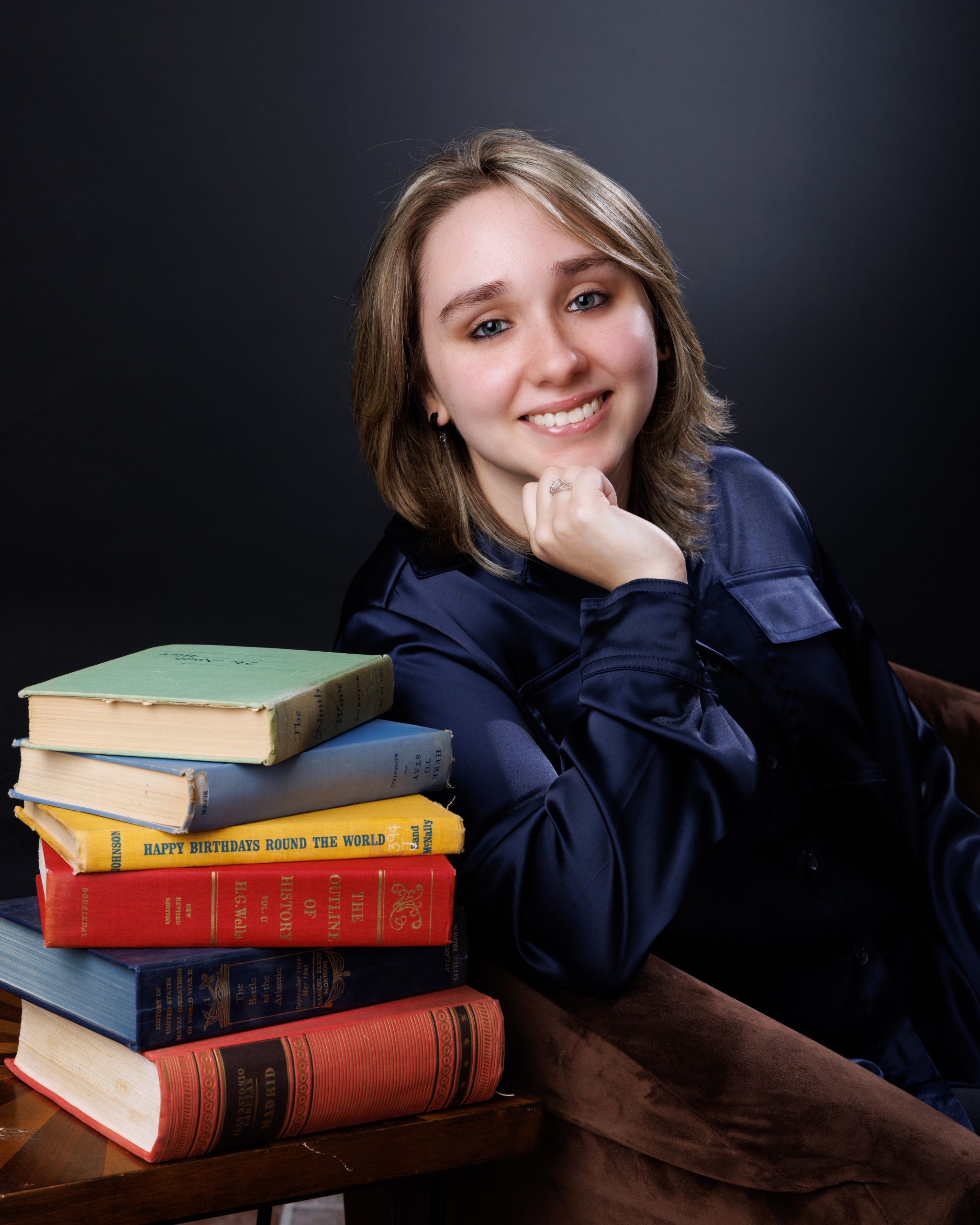 Emma seated with vintage luggage and rustic background for Downriver photography
