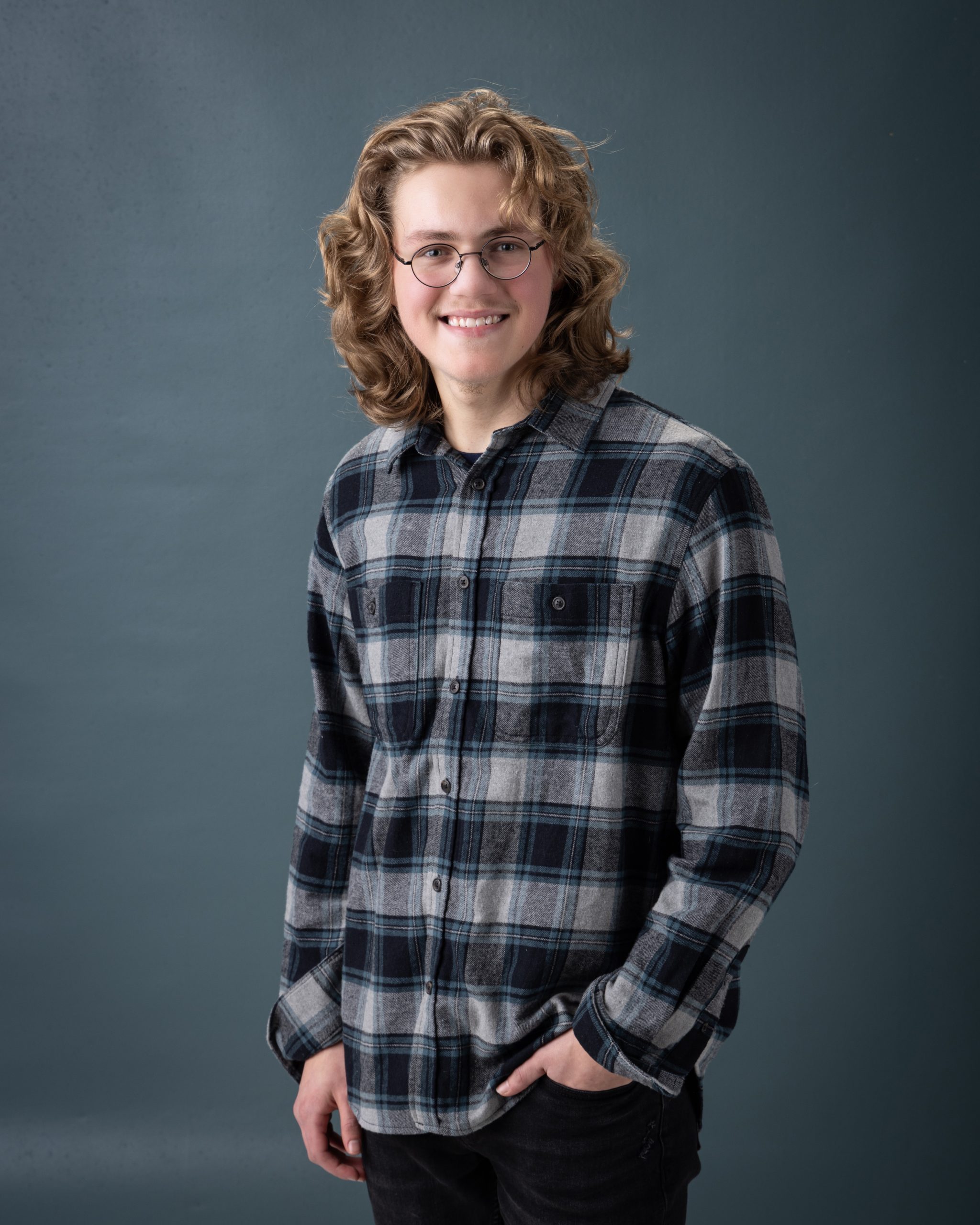 Allen Park senior photo session featuring Gavin with plaid shirt, seated pose, and light blue backdrop