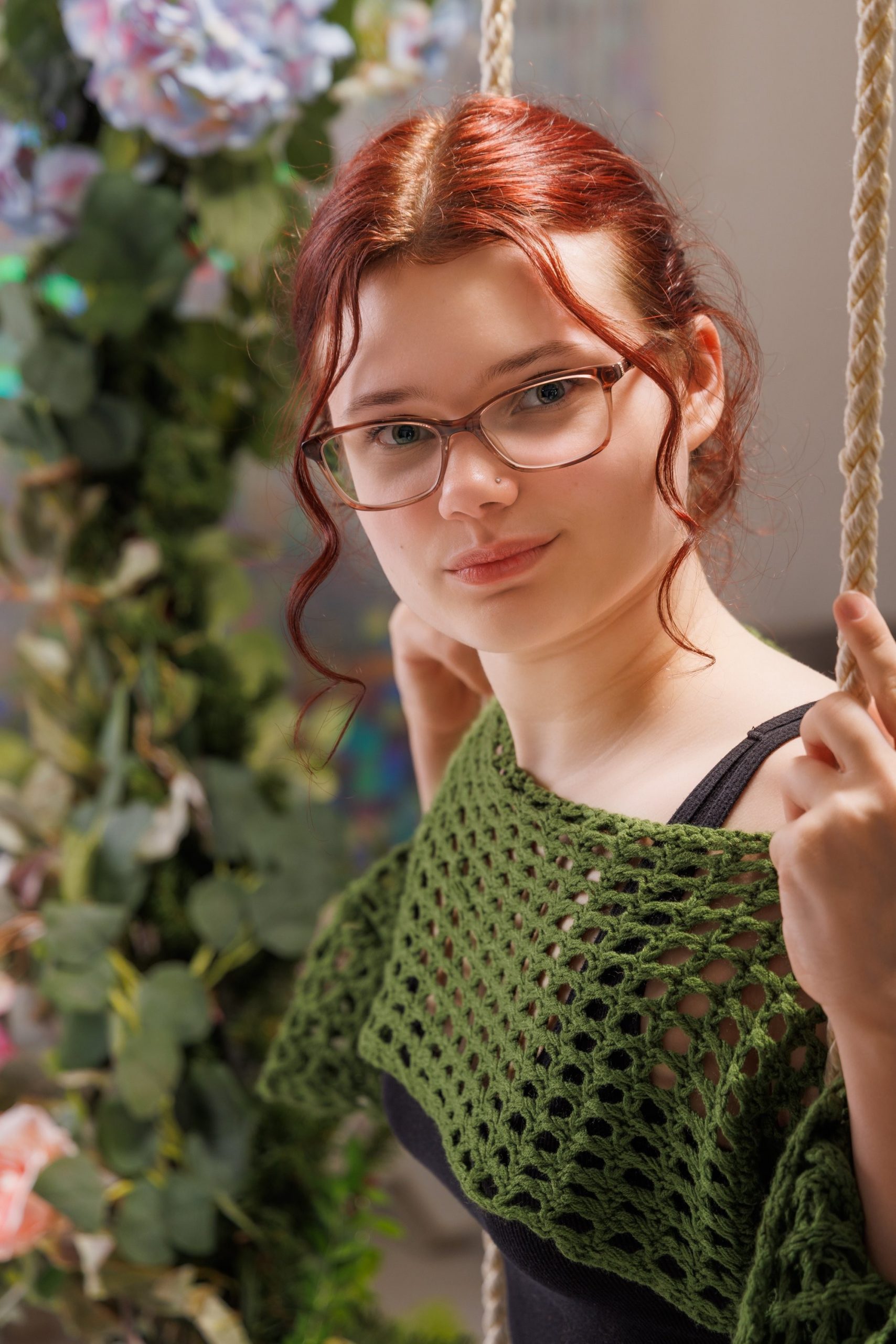 Senior portrait of Grace wearing a blue and green floral dress against a stone wall backdrop