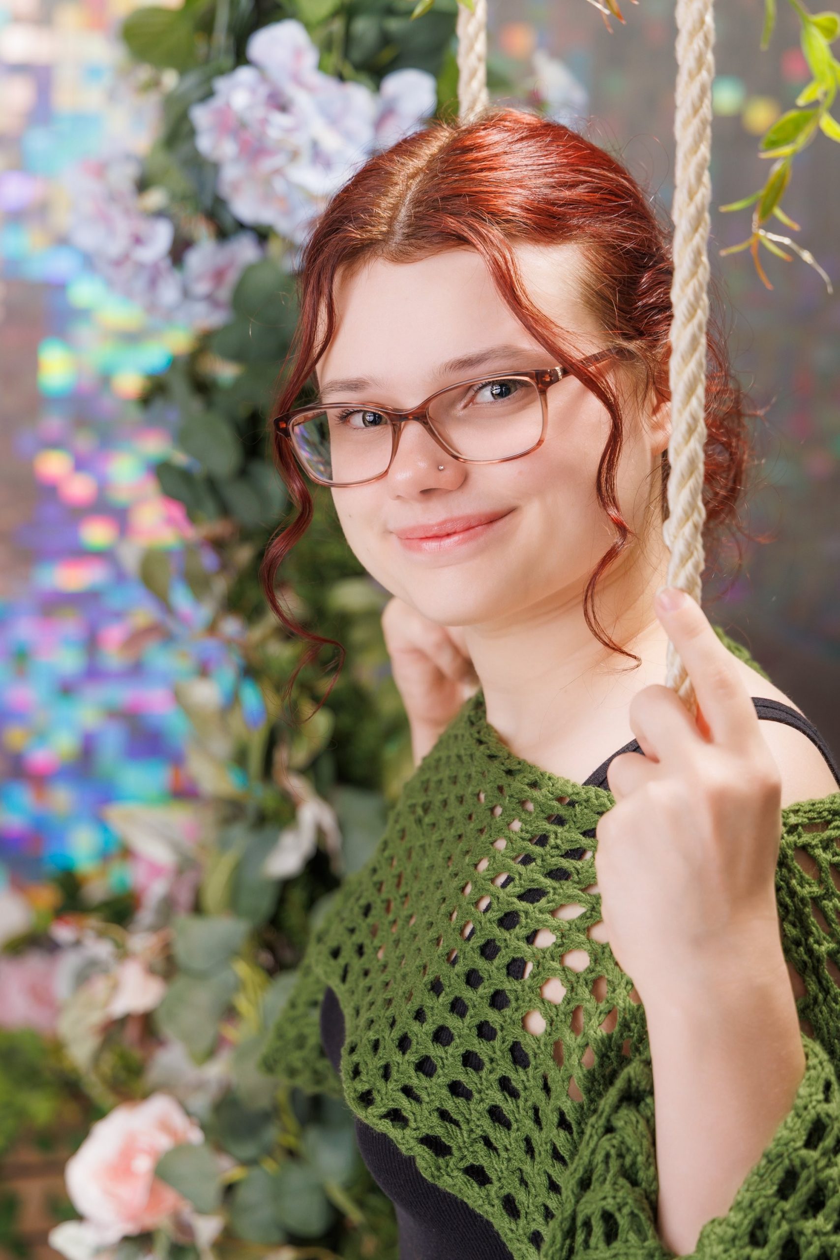 Senior portrait of Grace wearing a blue and green floral dress against a stone wall backdrop