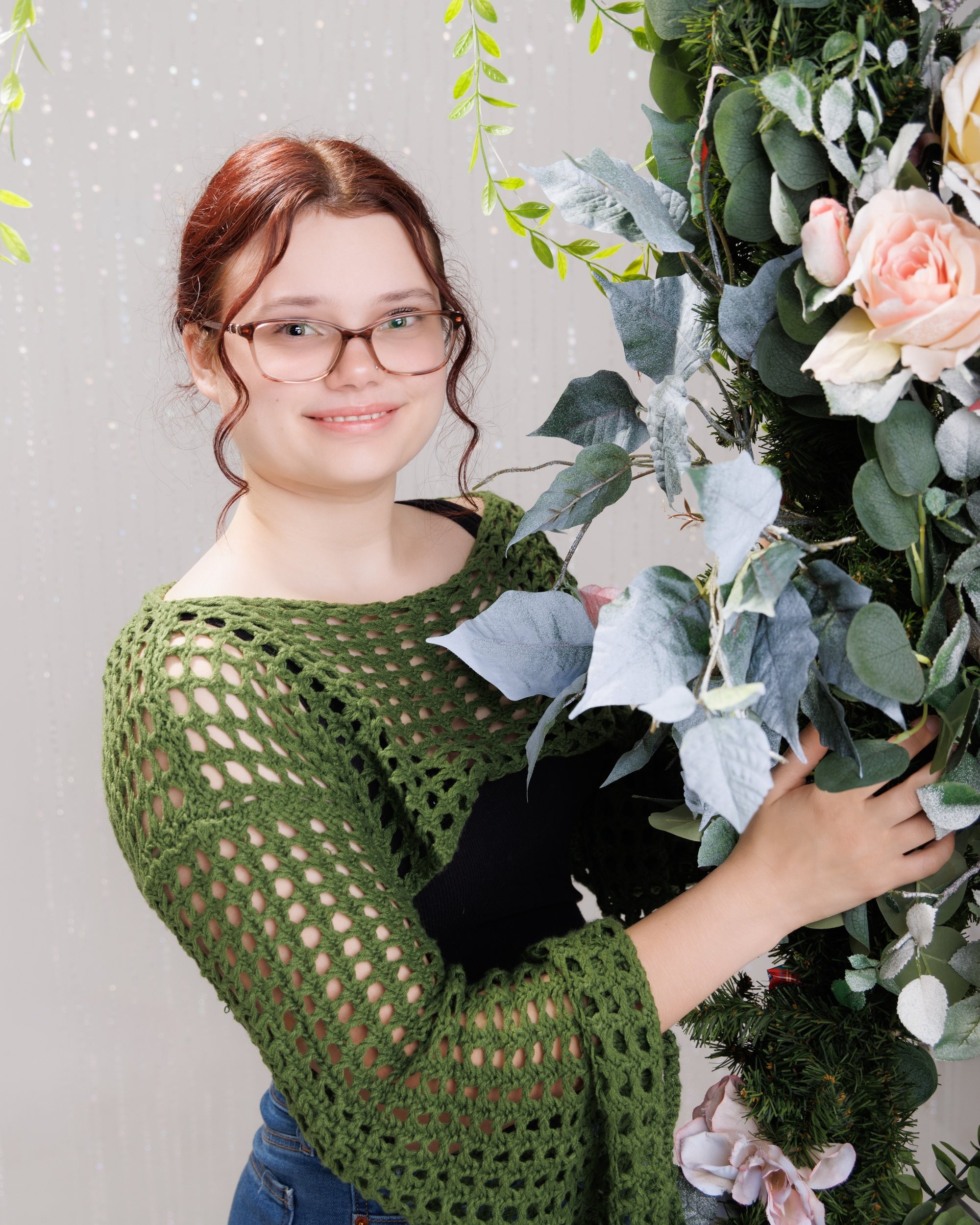 Senior portrait of Grace wearing a blue and green floral dress against a stone wall backdrop
