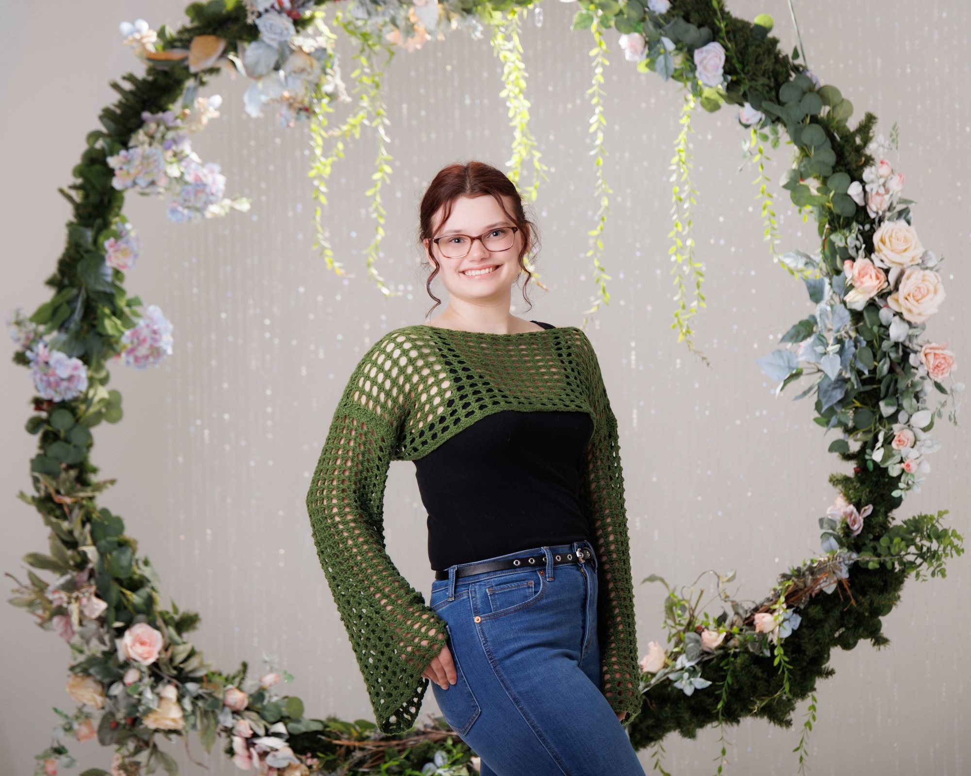 Senior portrait of Grace wearing a blue and green floral dress against a stone wall backdrop