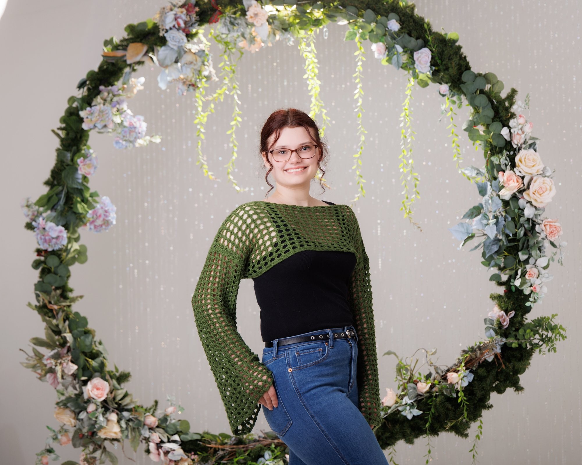 Senior portrait of Grace wearing a blue and green floral dress against a stone wall backdrop