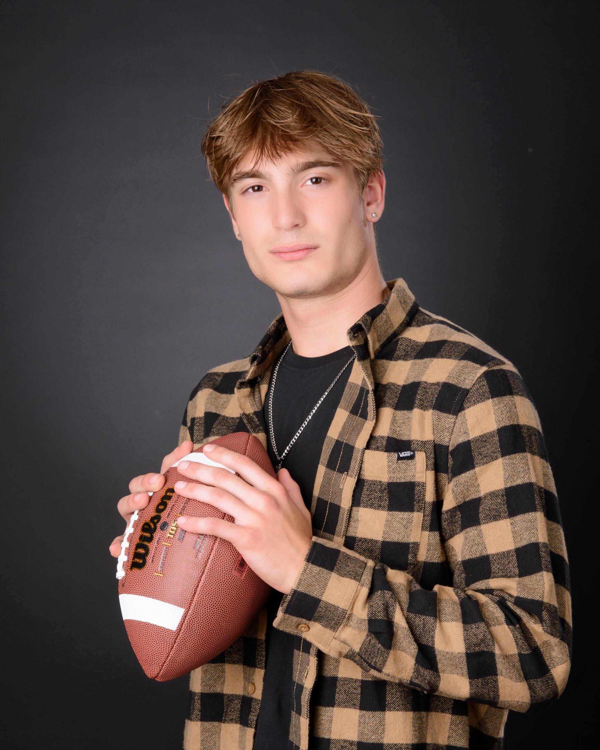 dark background senior photo session featuring ripped jeans and cross necklace