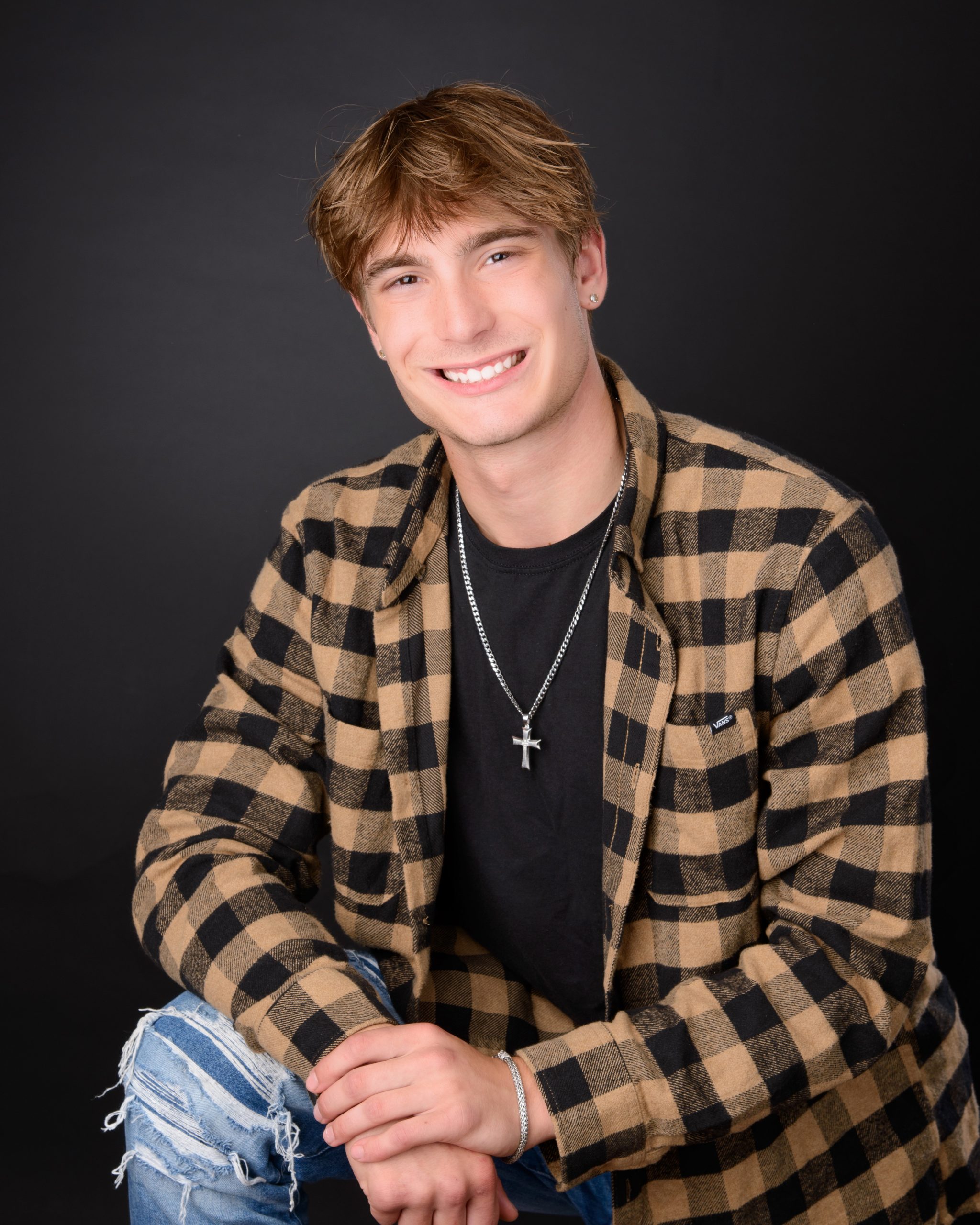 dark backdrop senior photography portrait with relaxed pose