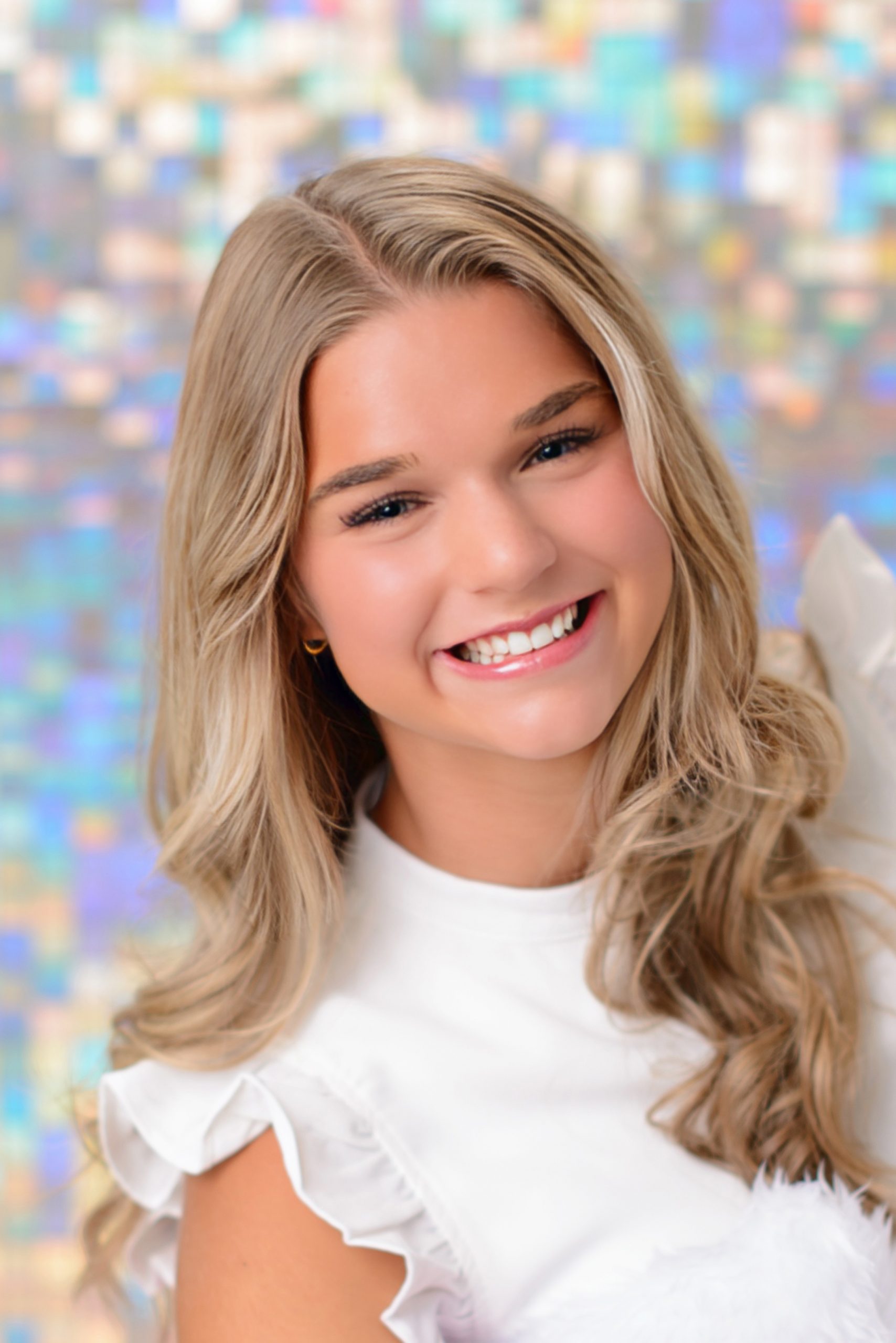 Morgan posing confidently in front of colorful mosaic wall during Downriver senior photo shoot