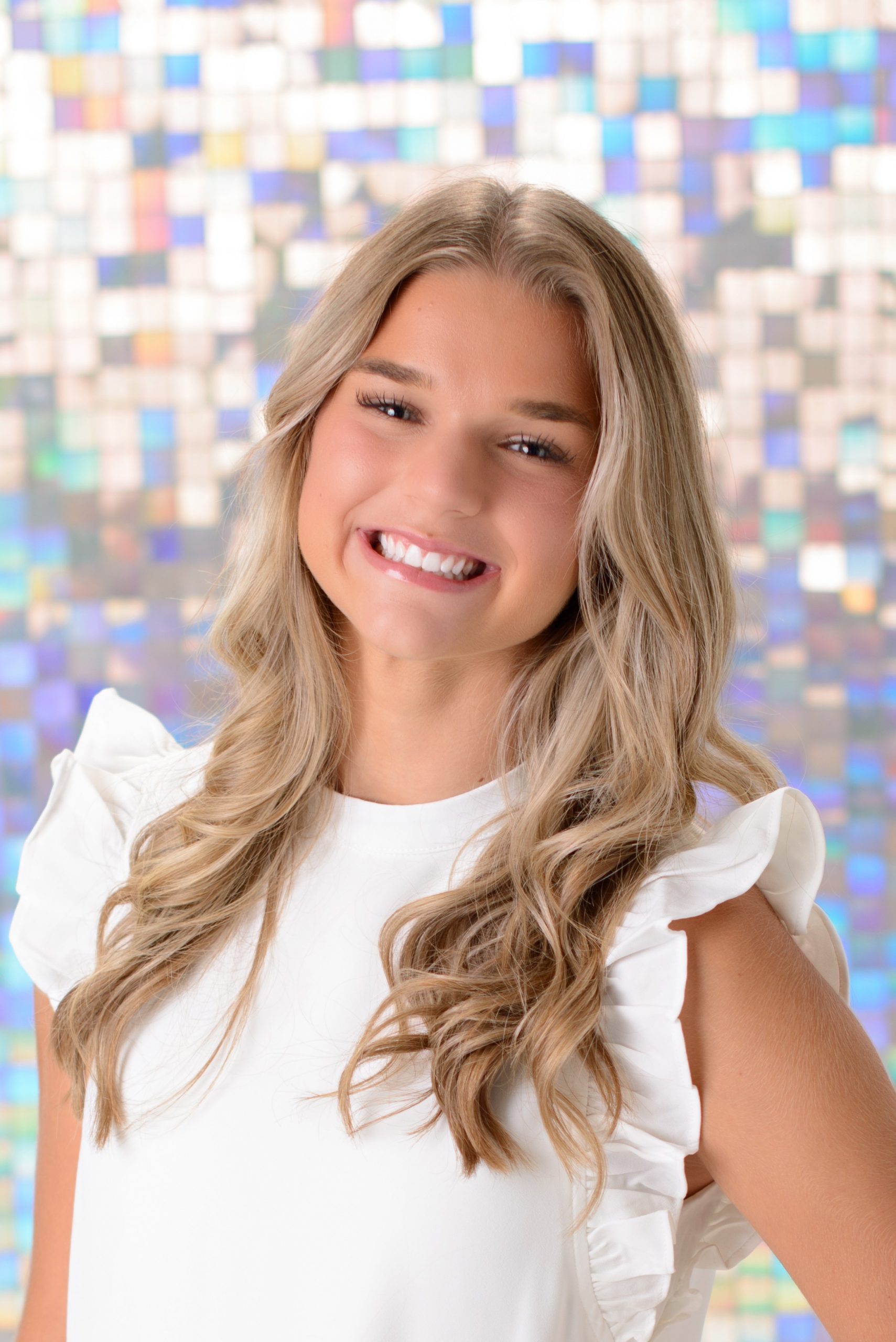 Morgan posing confidently in front of colorful mosaic wall during Downriver senior photo shoot