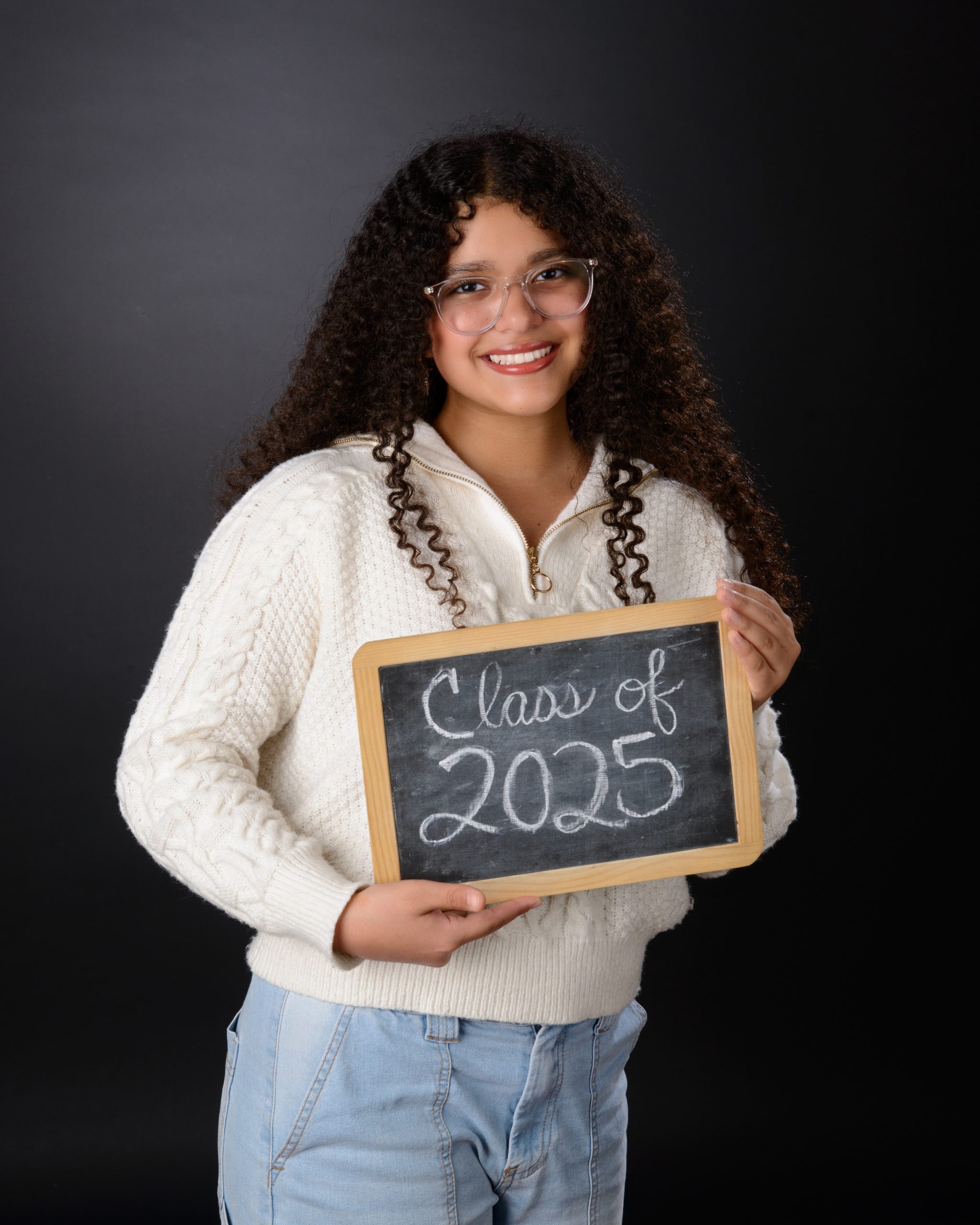 Senior student holds 'Class of 2025' chalkboard sign for Allen Park school photography session