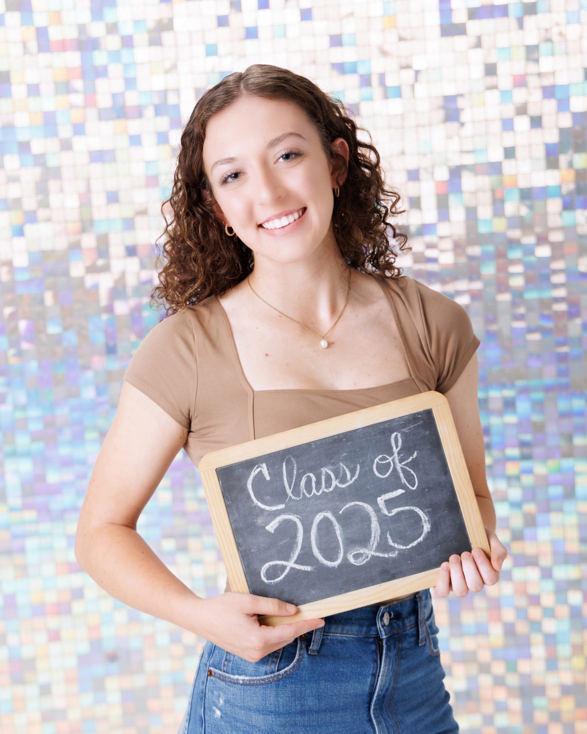 Graduation portrait of Melody holding 'Class of 2025' chalkboard, Downriver studio session
