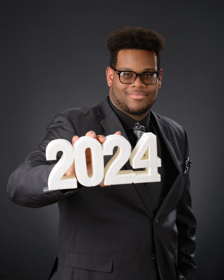 Senior portrait holding '2024' numbers in a formal suit
