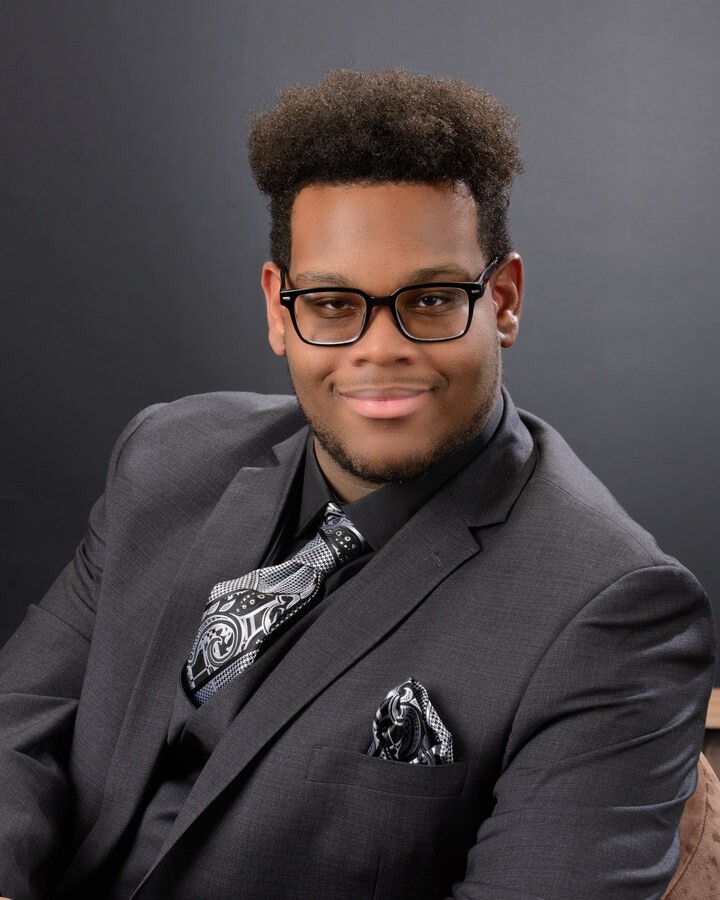 Formal headshot of senior student in vest and tie, arms crossed