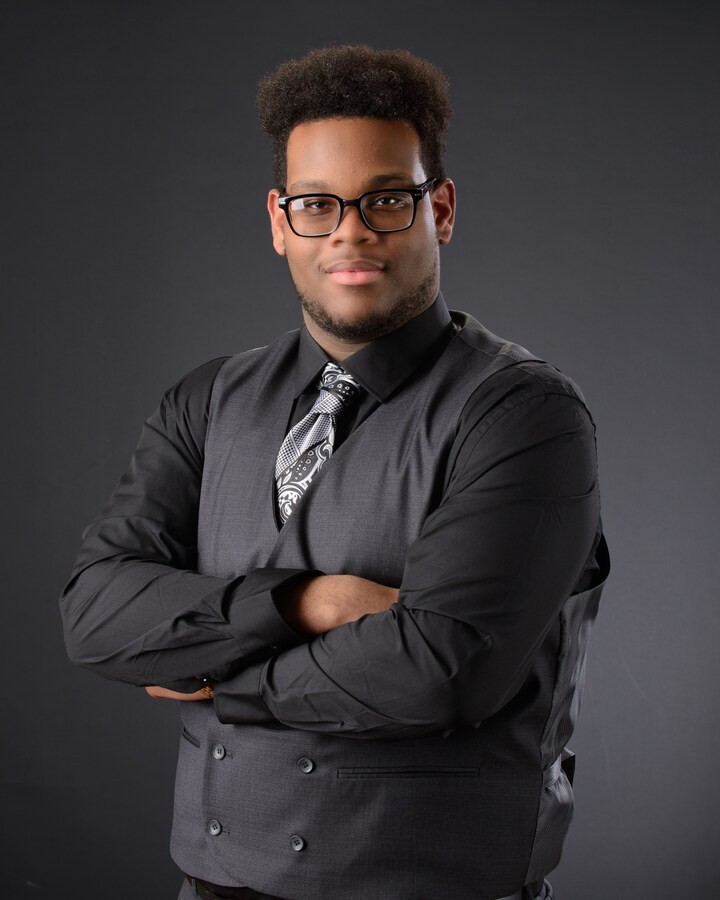 Formal headshot of senior student in vest and tie, arms crossed