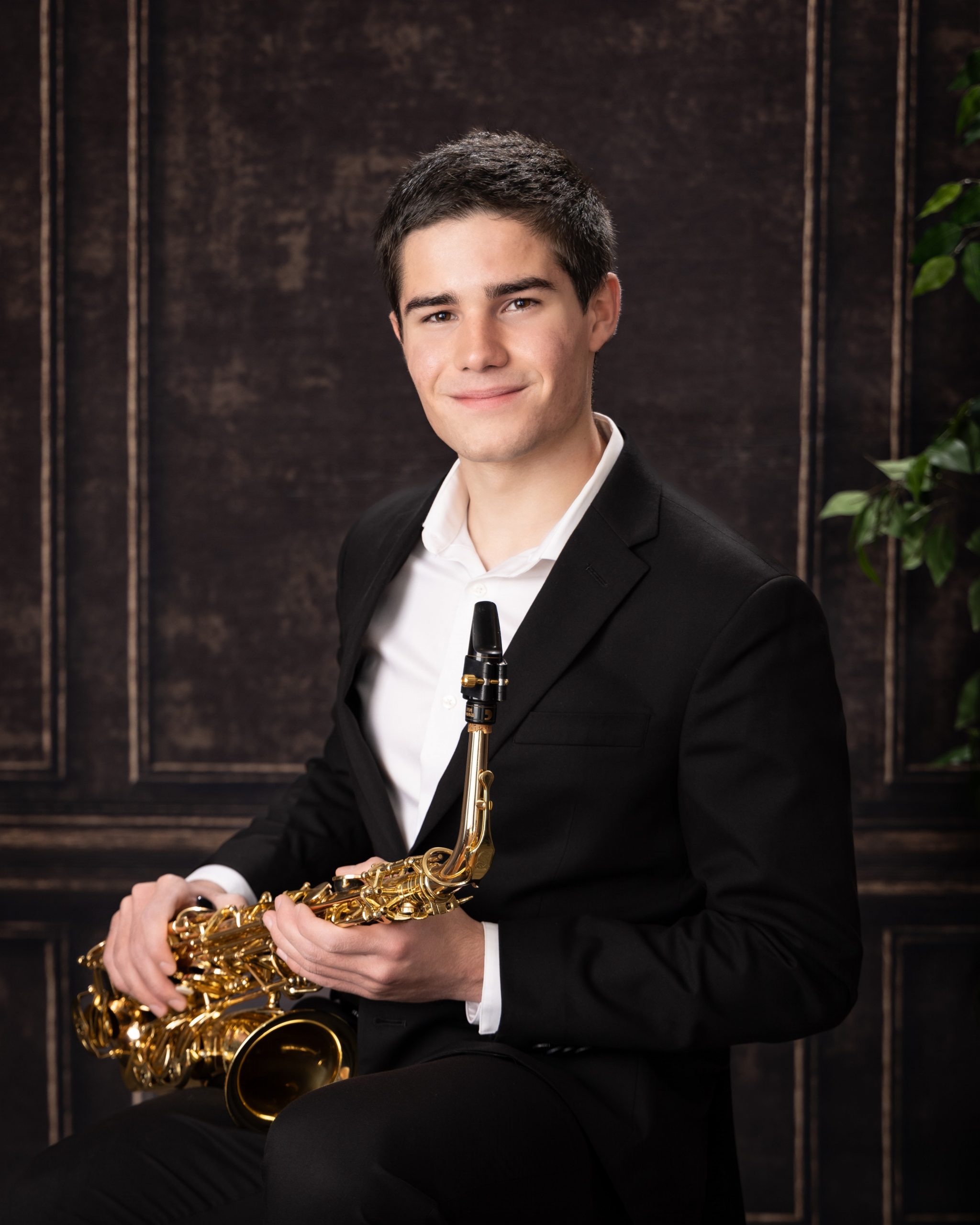 Male student holding saxophone in formal portrait setup
