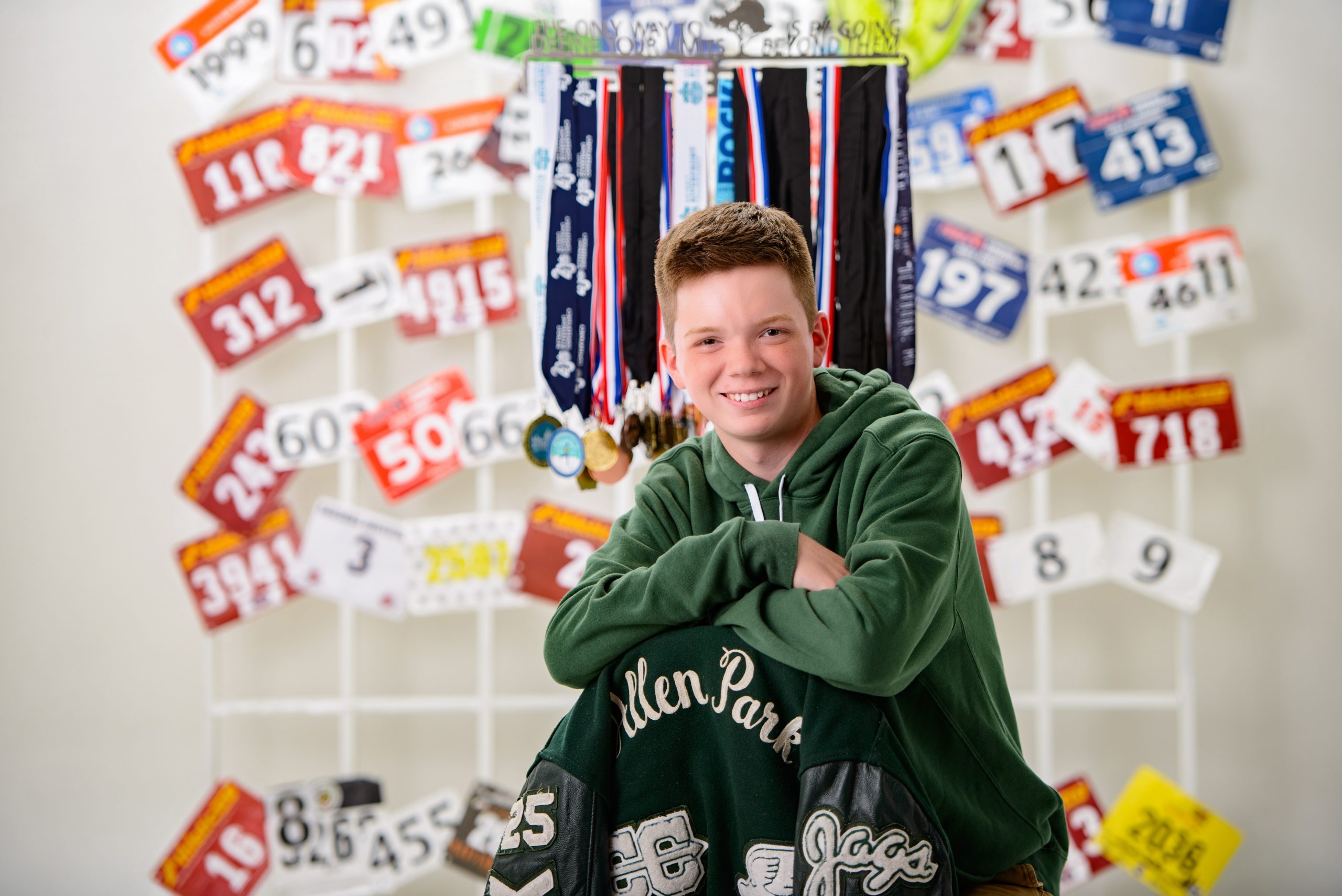 Allen Park track runner senior photo session with race bibs and medals on wall