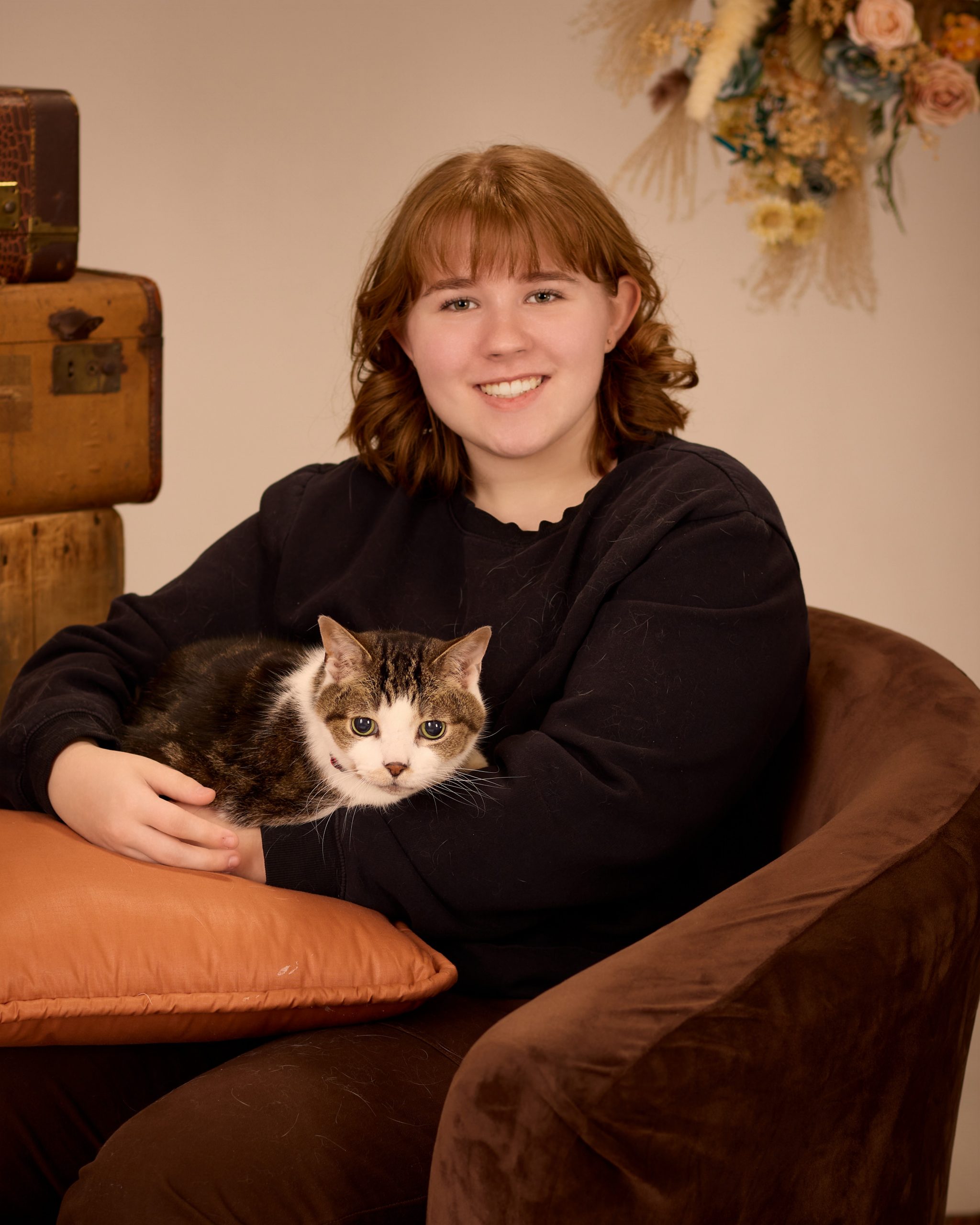Evelyn seated with vintage luggage and candle lighting in Downriver studio session