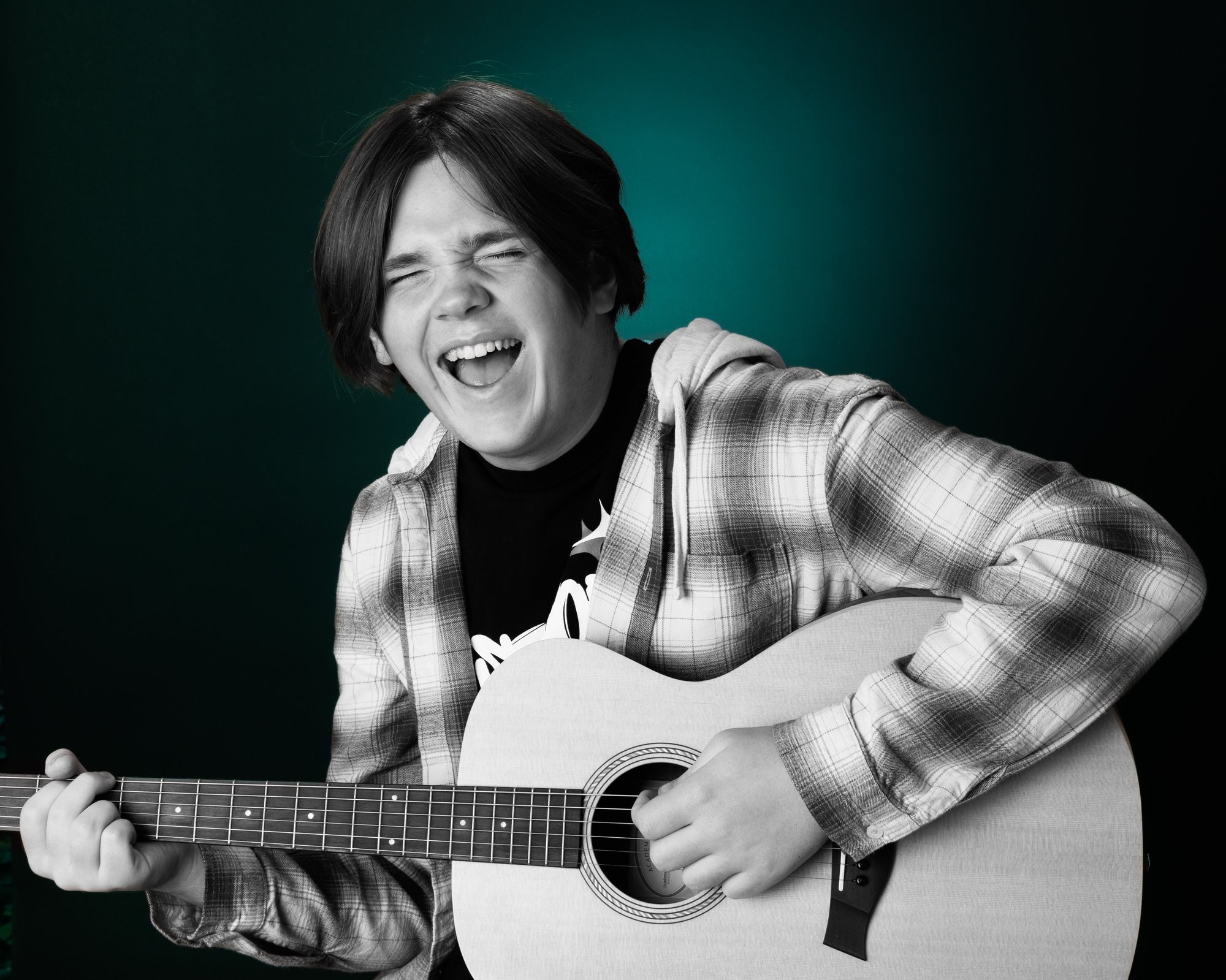 Senior portrait featuring an acoustic guitar against a dark gradient background, showcasing the artist's style in our Taylor photo studio