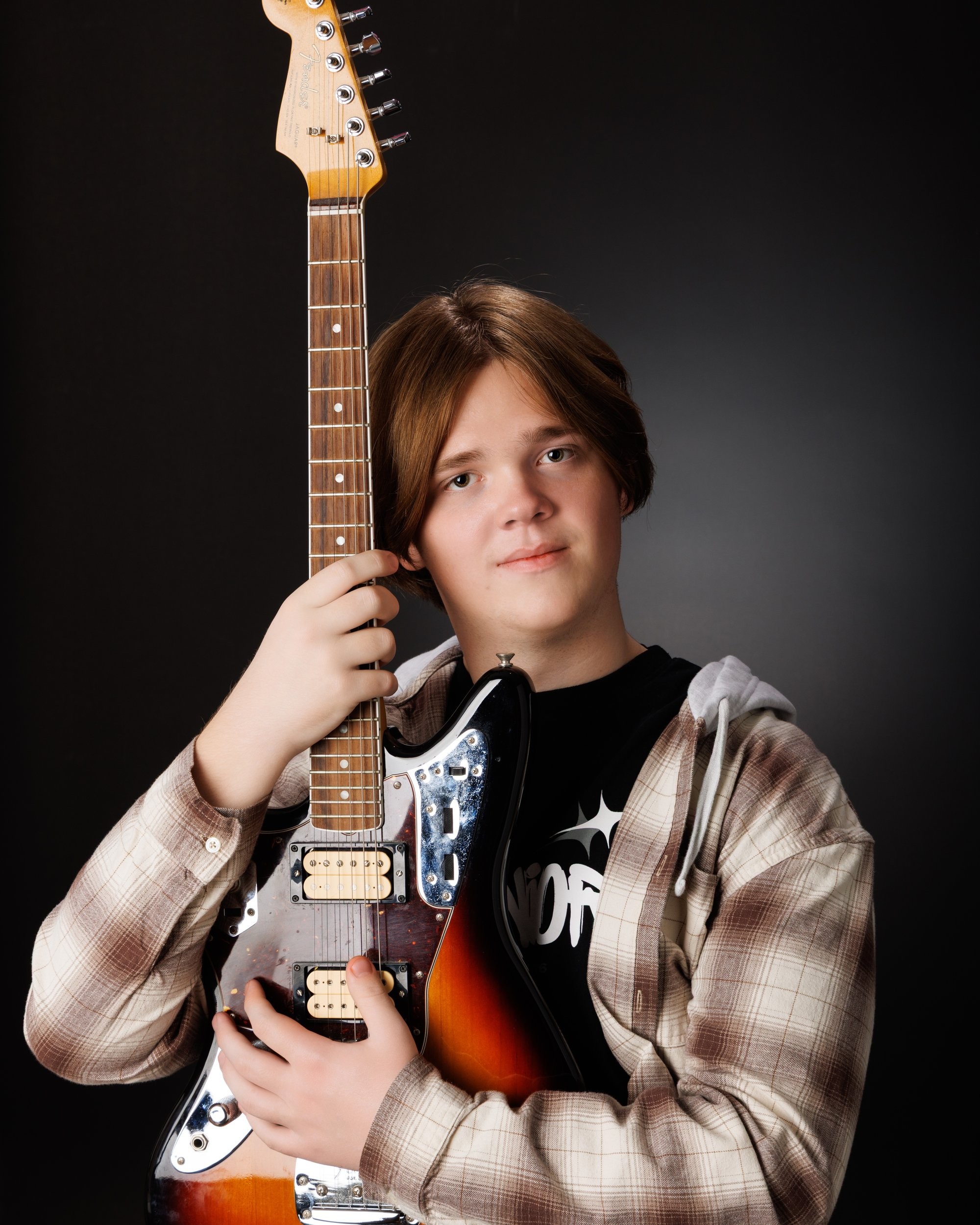 Senior portrait featuring an acoustic guitar against a dark gradient background, showcasing the artist's style in our Taylor photo studio