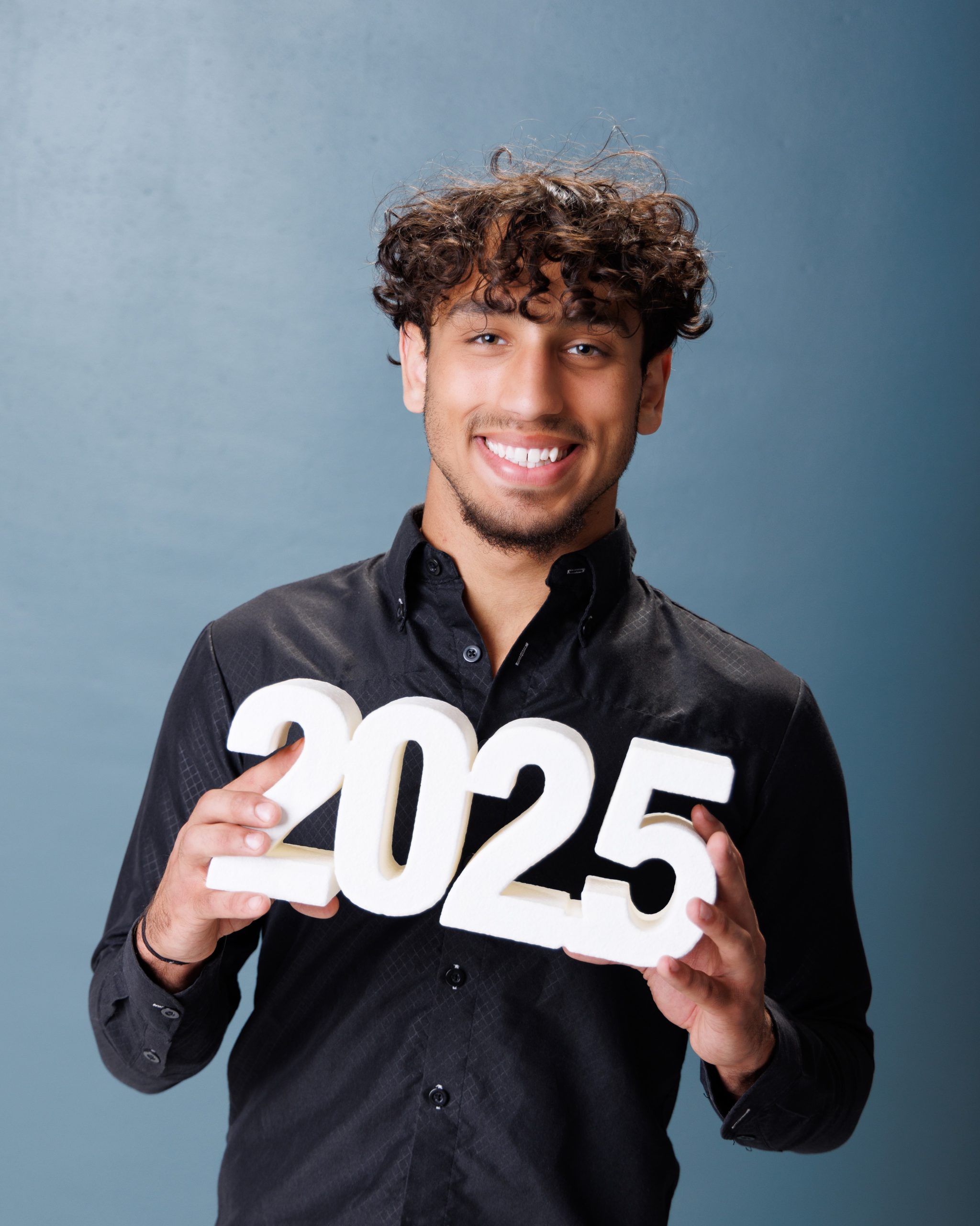 senior student holding 2025 graduation numbers in studio session