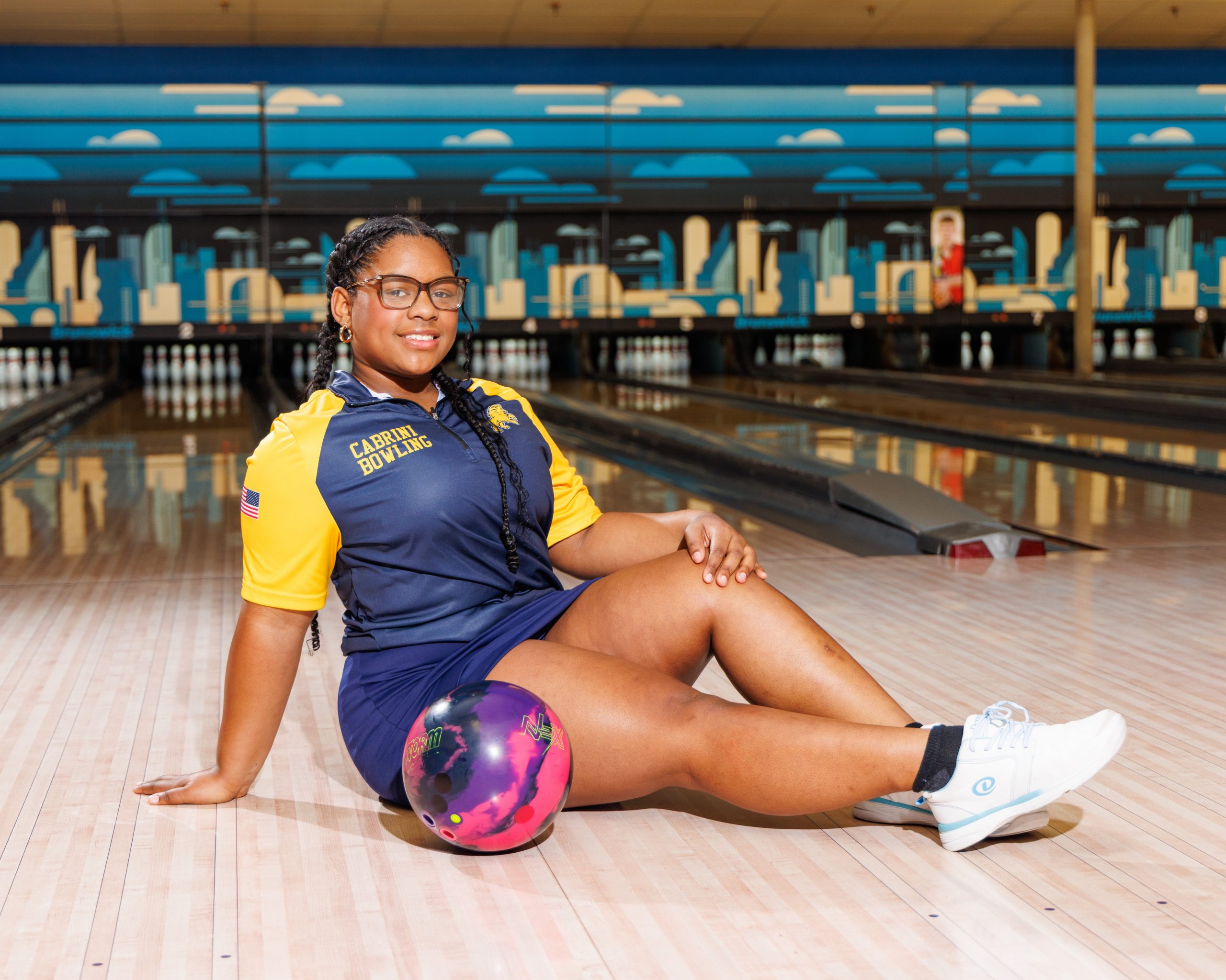 Cabrini Bowling player lying on floor with red bowling ball