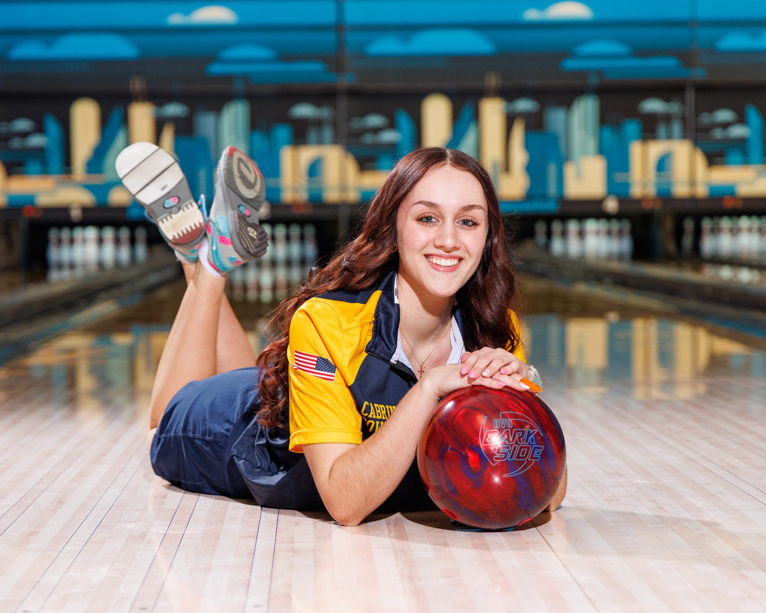 Cabrini Bowling player lying on floor with red bowling ball