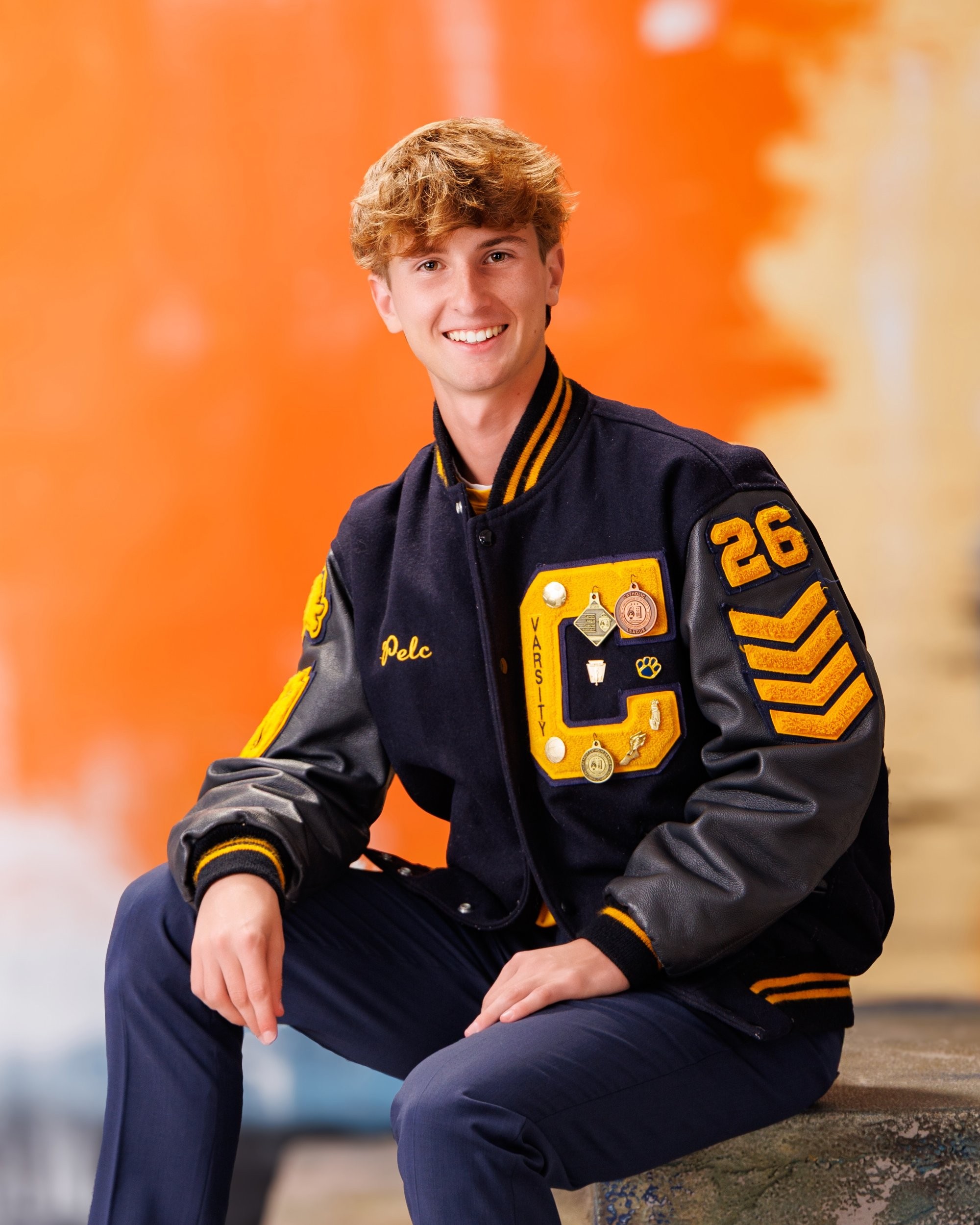 Cabrini High senior Brad posing with a varsity backpack featuring sports logos and 'Laborini' text, showcasing school spirit in a minimalist studio setting.