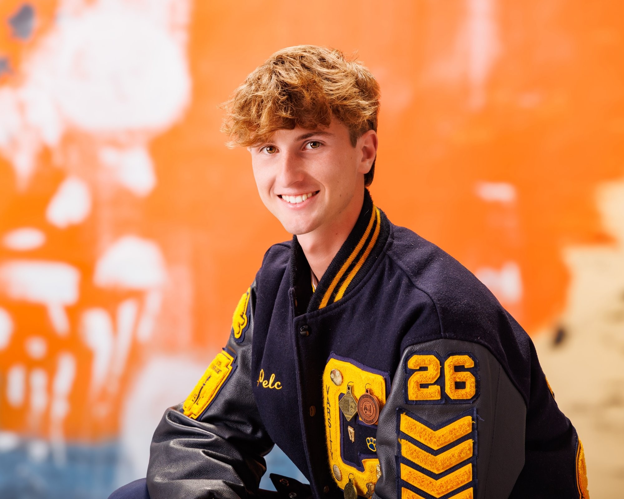 Cabrini High senior Brad posing with a varsity backpack featuring sports logos and 'Laborini' text, showcasing school spirit in a minimalist studio setting.