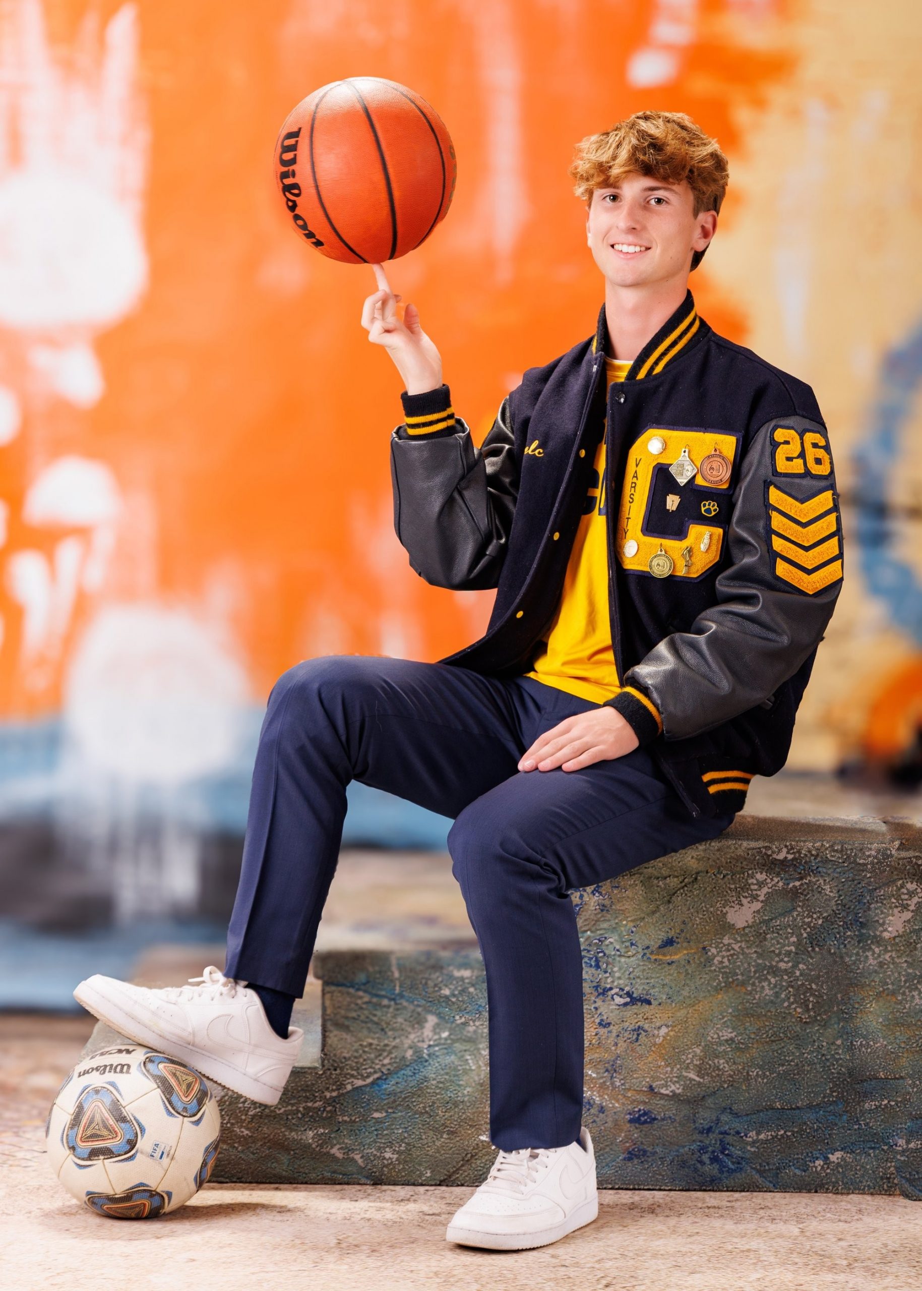 Cabrini High senior Brad posing with a varsity backpack featuring sports logos and 'Laborini' text, showcasing school spirit in a minimalist studio setting.