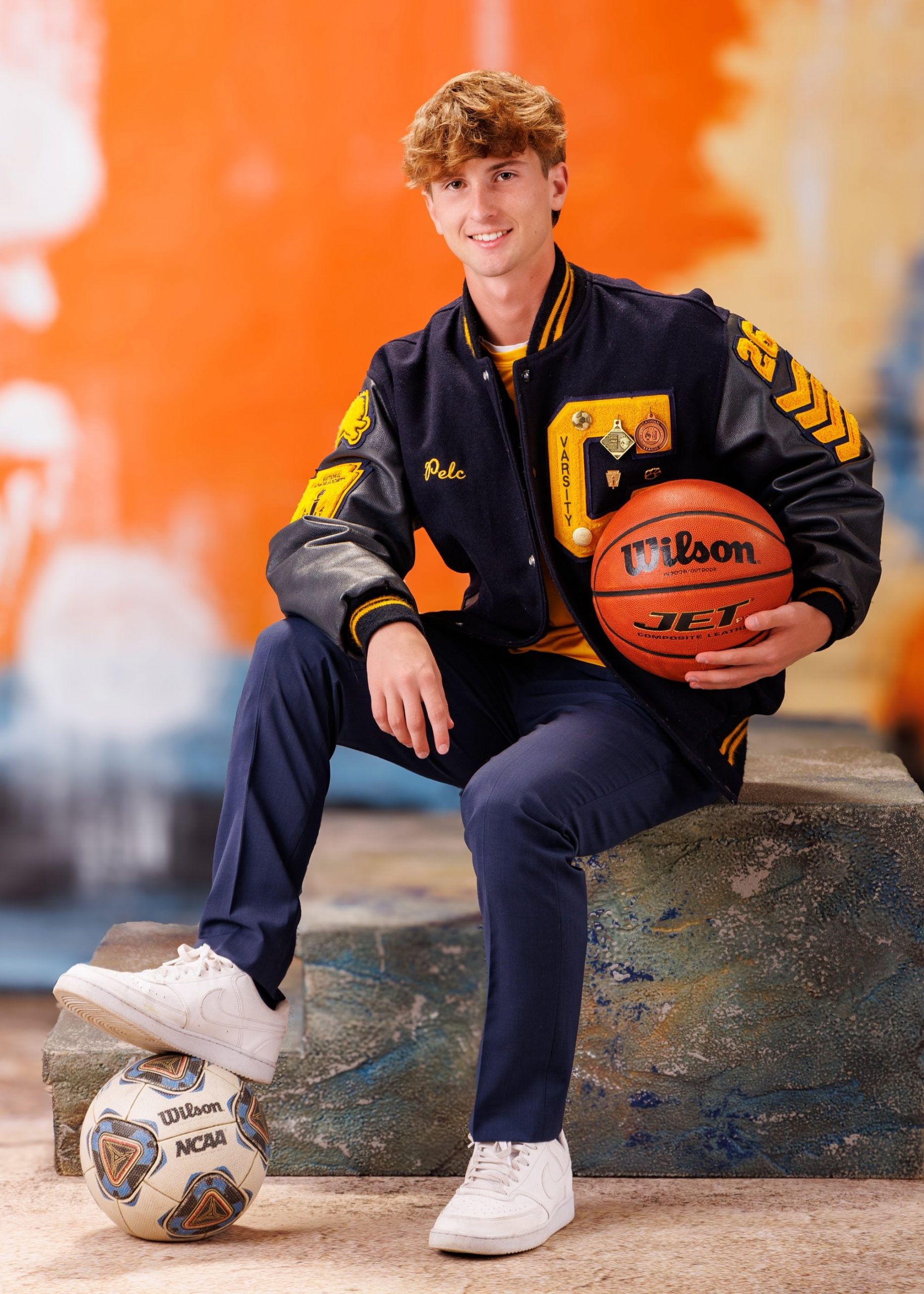 Cabrini High senior Brad posing with a varsity backpack featuring sports logos and 'Laborini' text, showcasing school spirit in a minimalist studio setting.