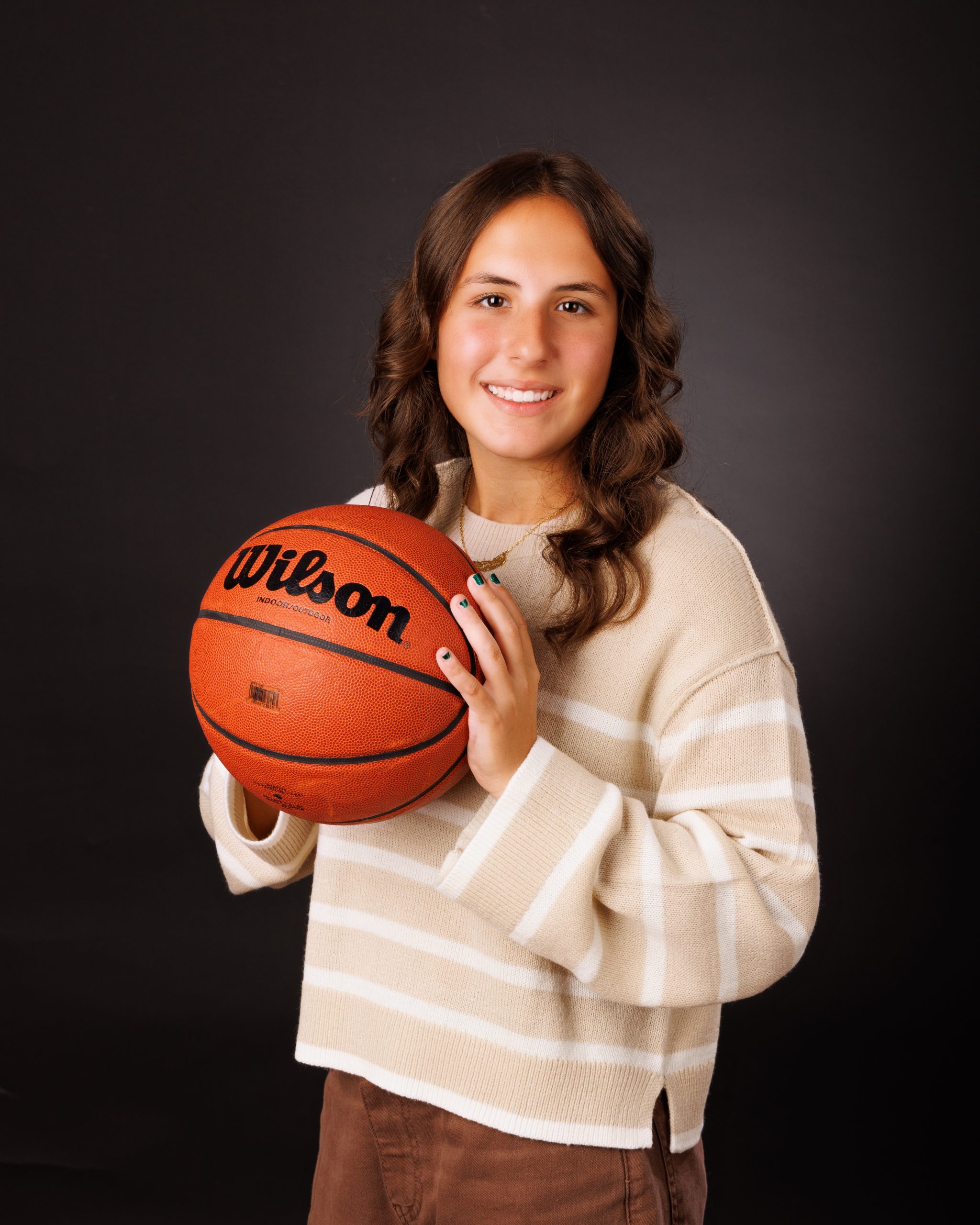 Isabella holding Wilson basketball in senior portrait for Cabrini School