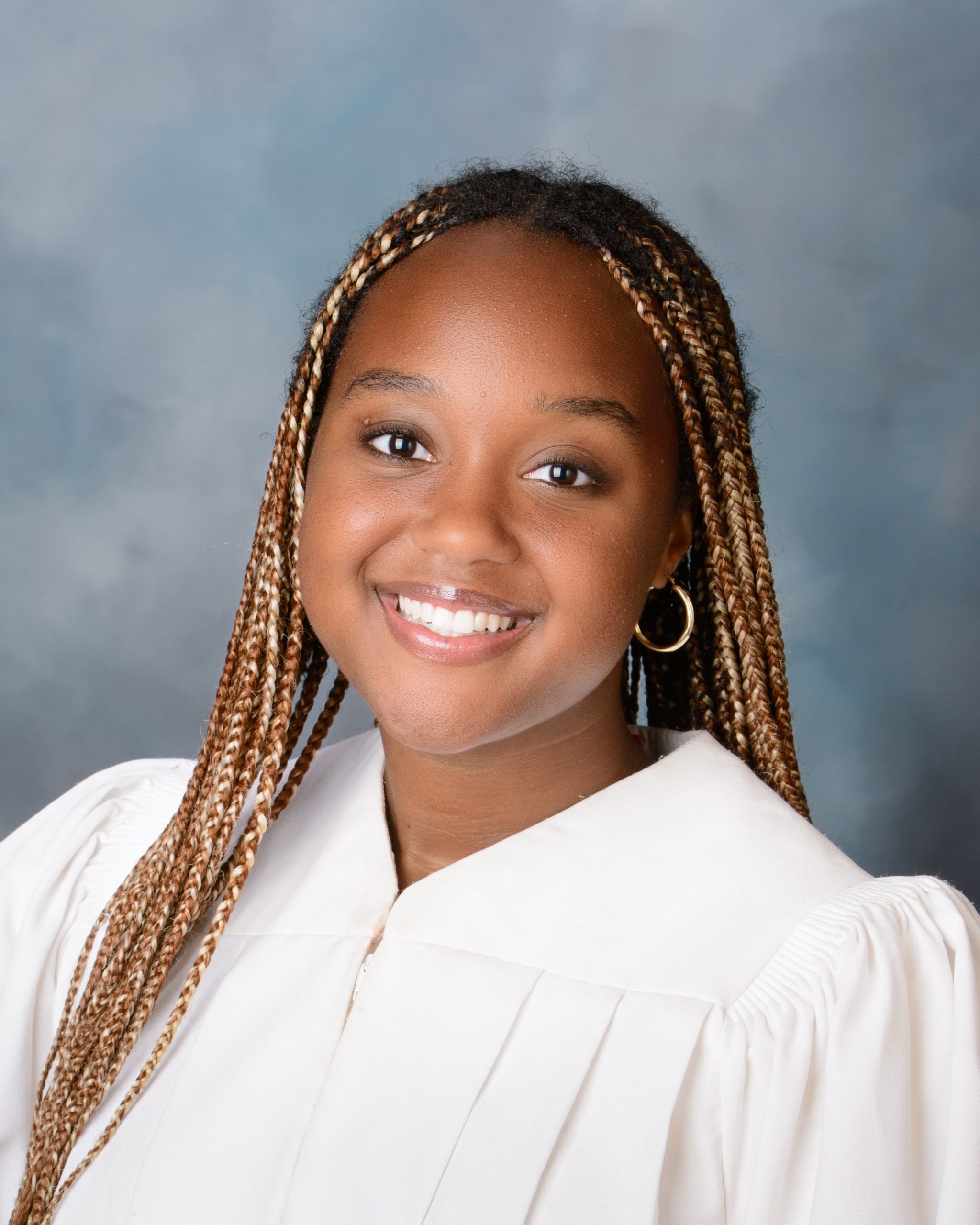 Cabrini Senior Faith in graduation gown, smiling during a senior photography session at our photo studio