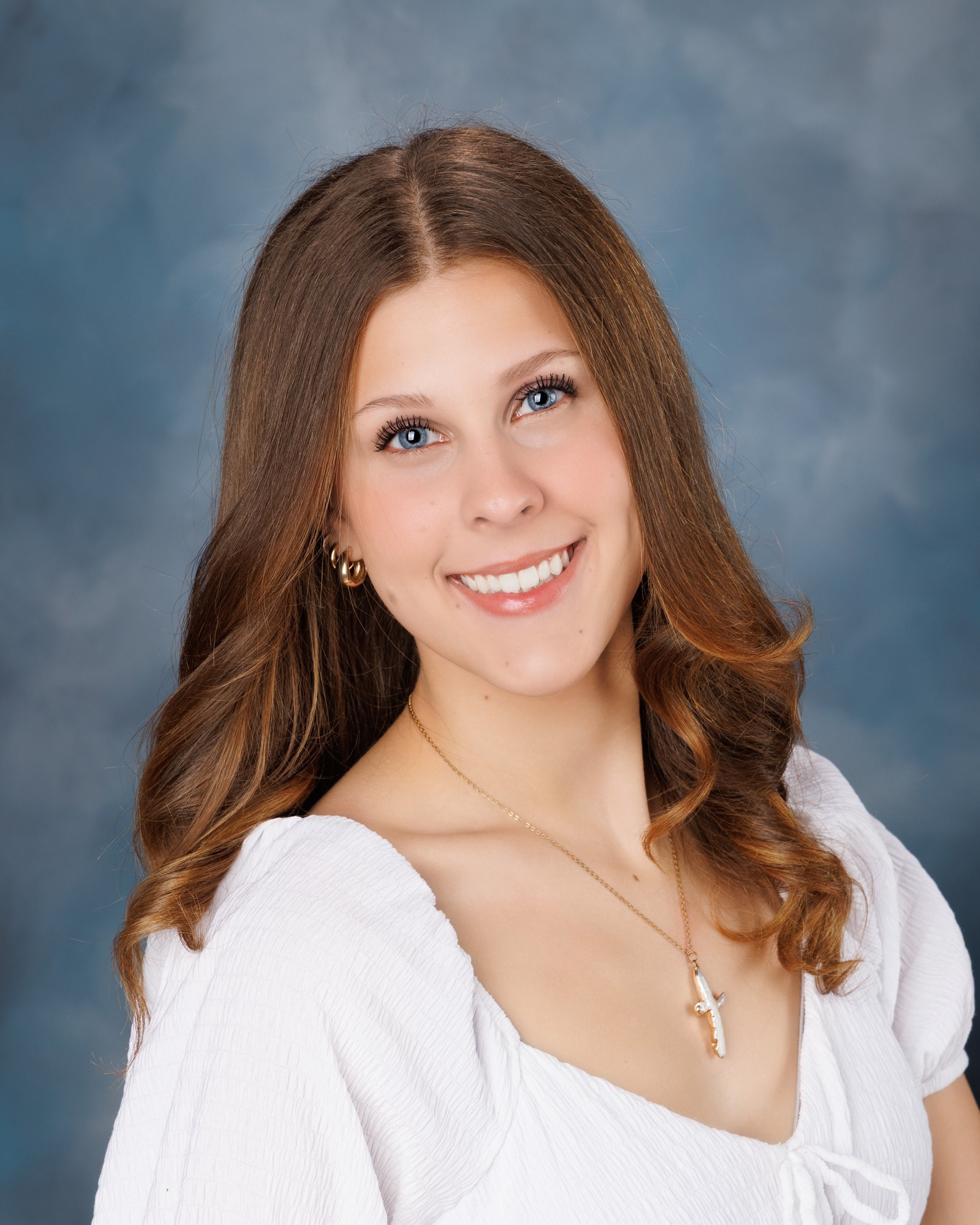 Cabrini Senior student Isabella's vibrant pink mosaic background portrait, white blouse, and cross necklace