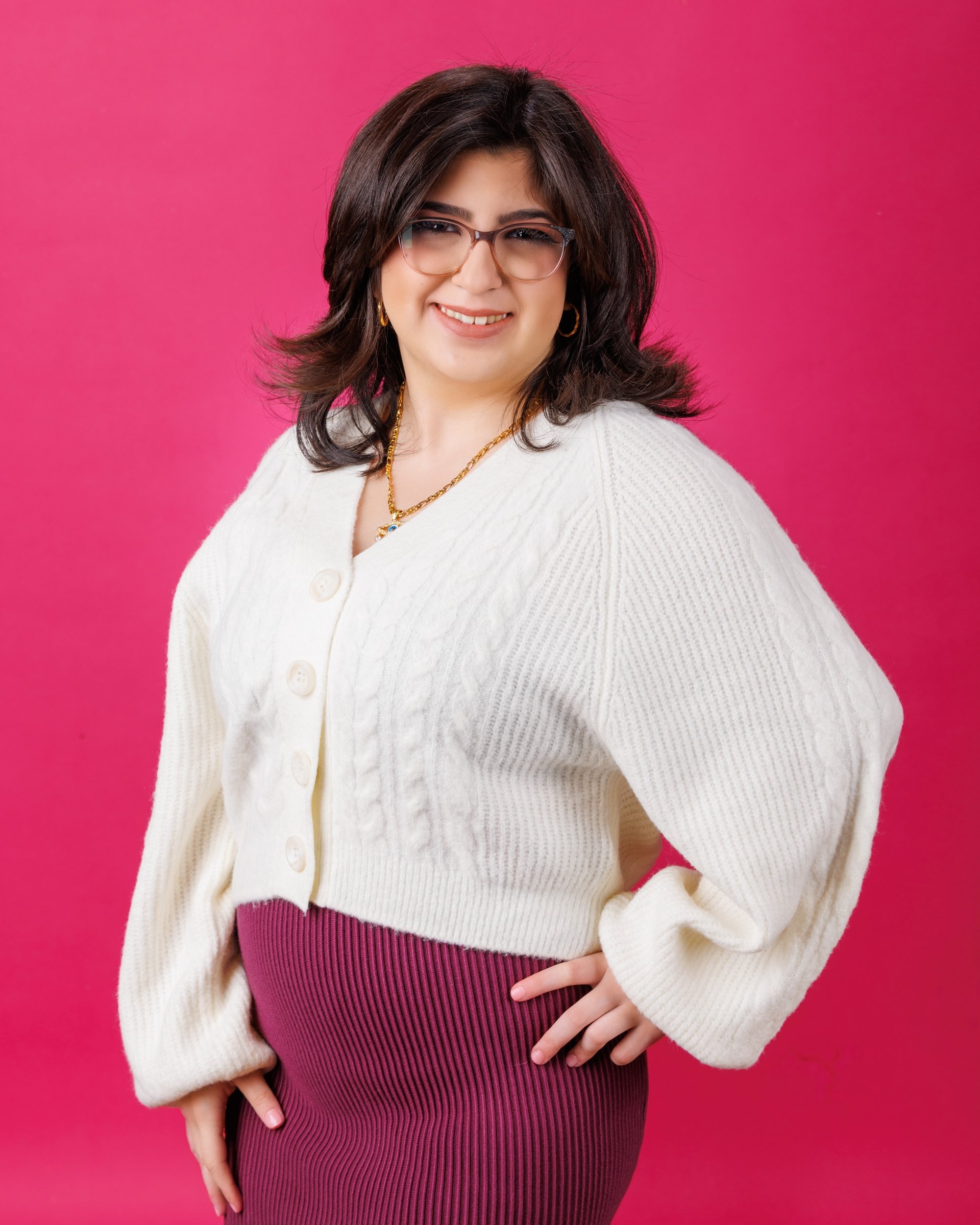 Cabrini Senior student Isabella's vibrant pink mosaic background portrait, white blouse, and cross necklace