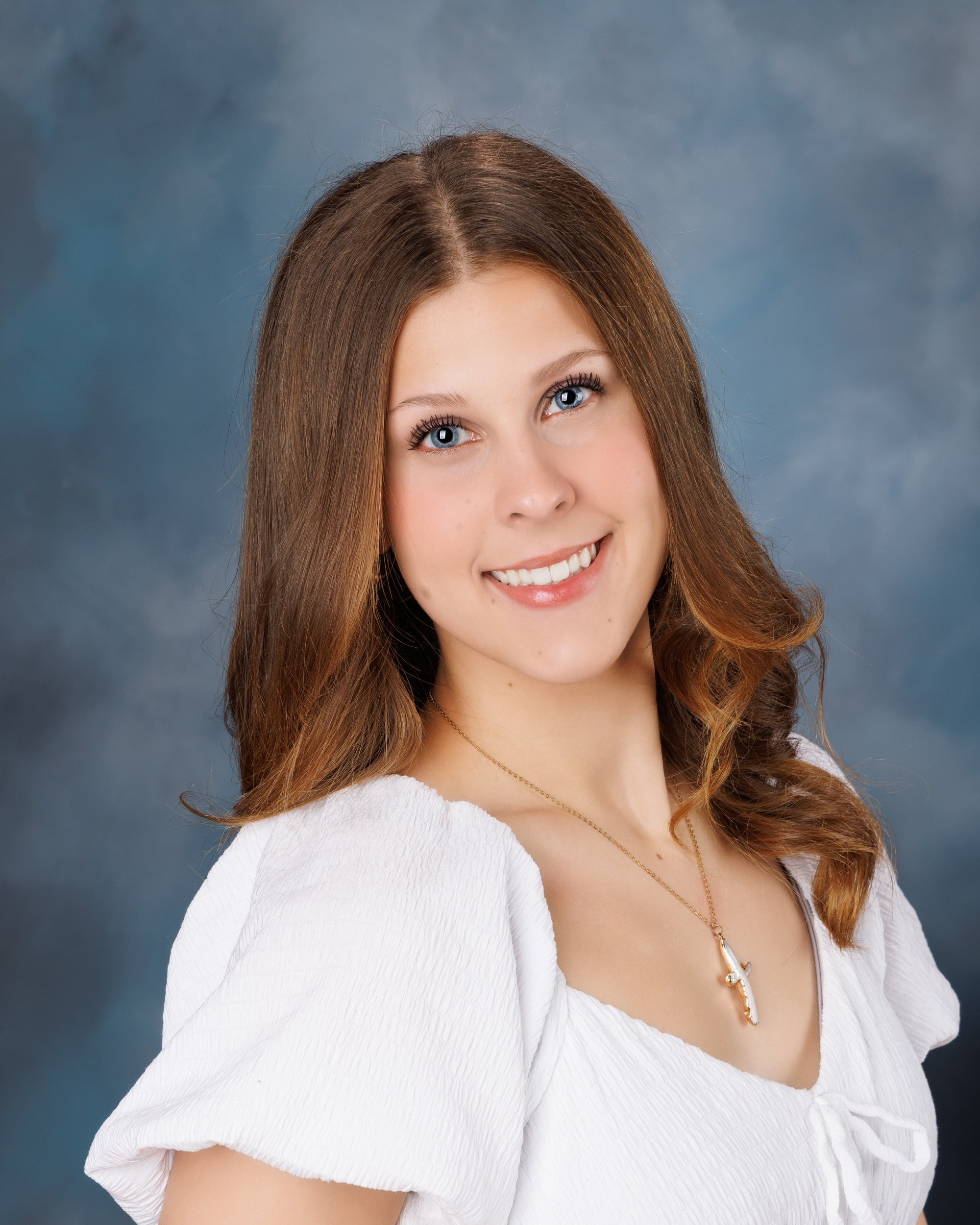 Cabrini Senior student Isabella's vibrant pink mosaic background portrait, white blouse, and cross necklace