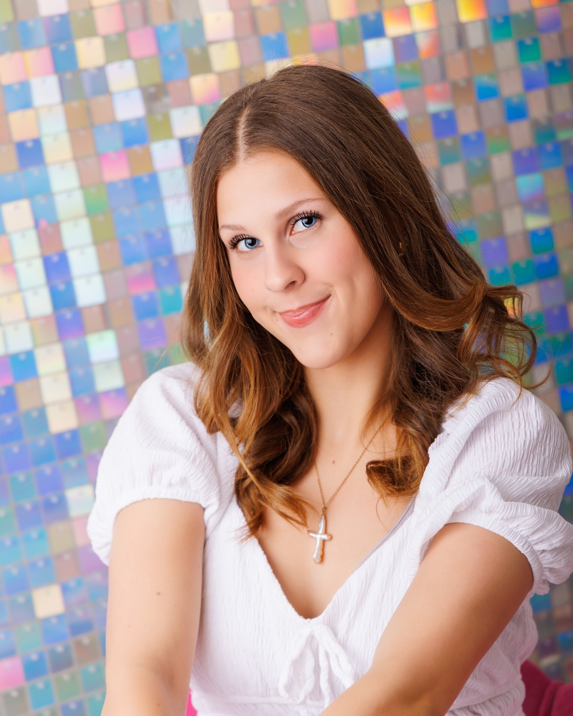 Cabrini Senior student Isabella's vibrant pink mosaic background portrait, white blouse, and cross necklace