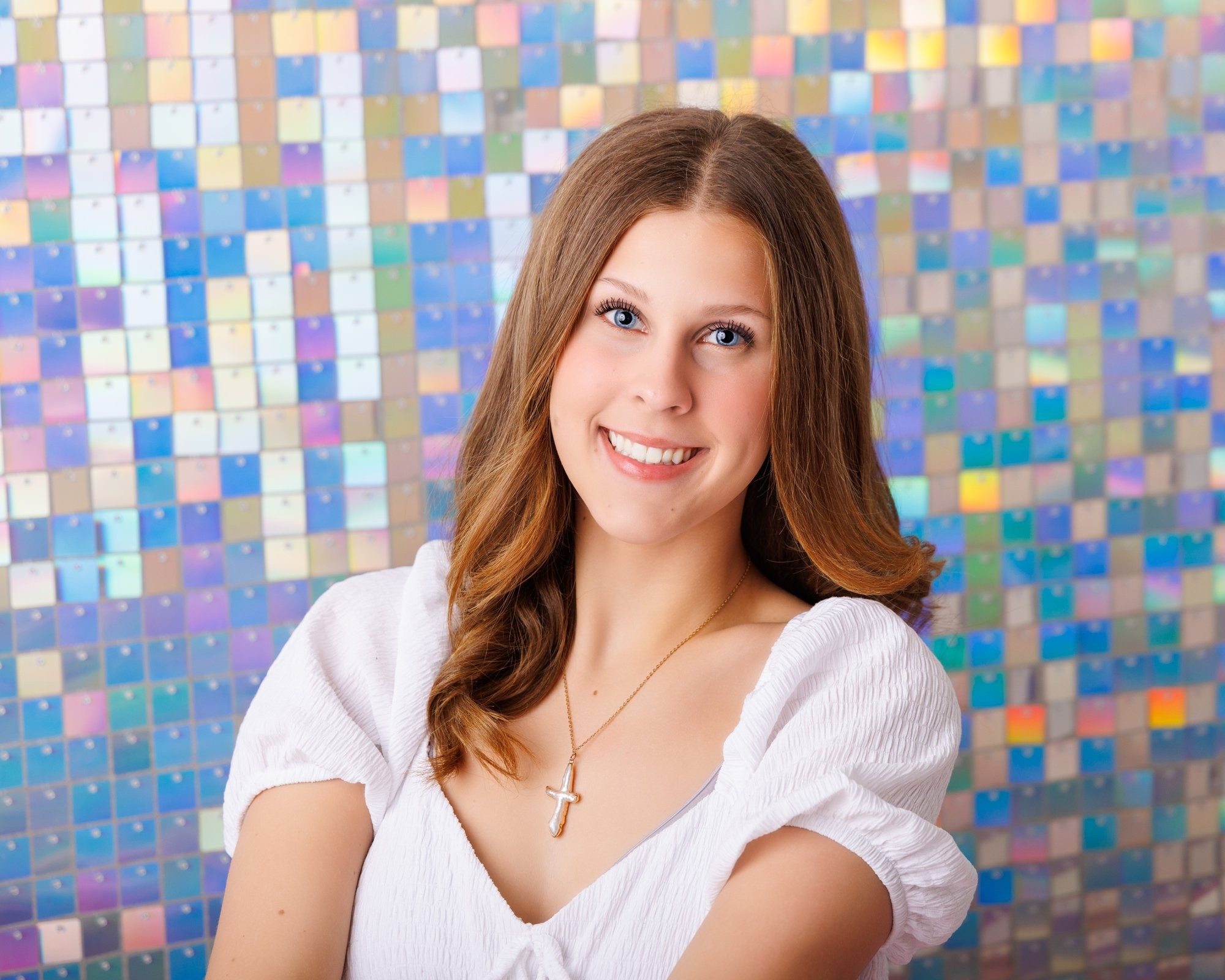 Cabrini Senior student Isabella's vibrant pink mosaic background portrait, white blouse, and cross necklace